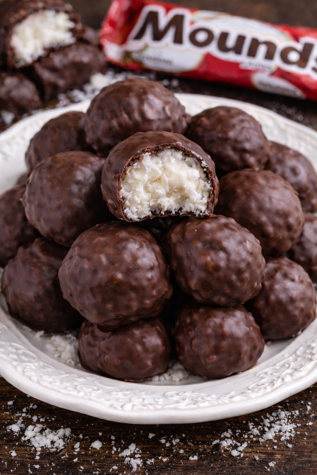 Mounds Coconut Copycat Chocolate Balls on a white pretty plate with a bite missing 