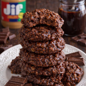 Chocolate Peanut Butter No Bake Cookies on a white plate stacked with a bite missing from the top one