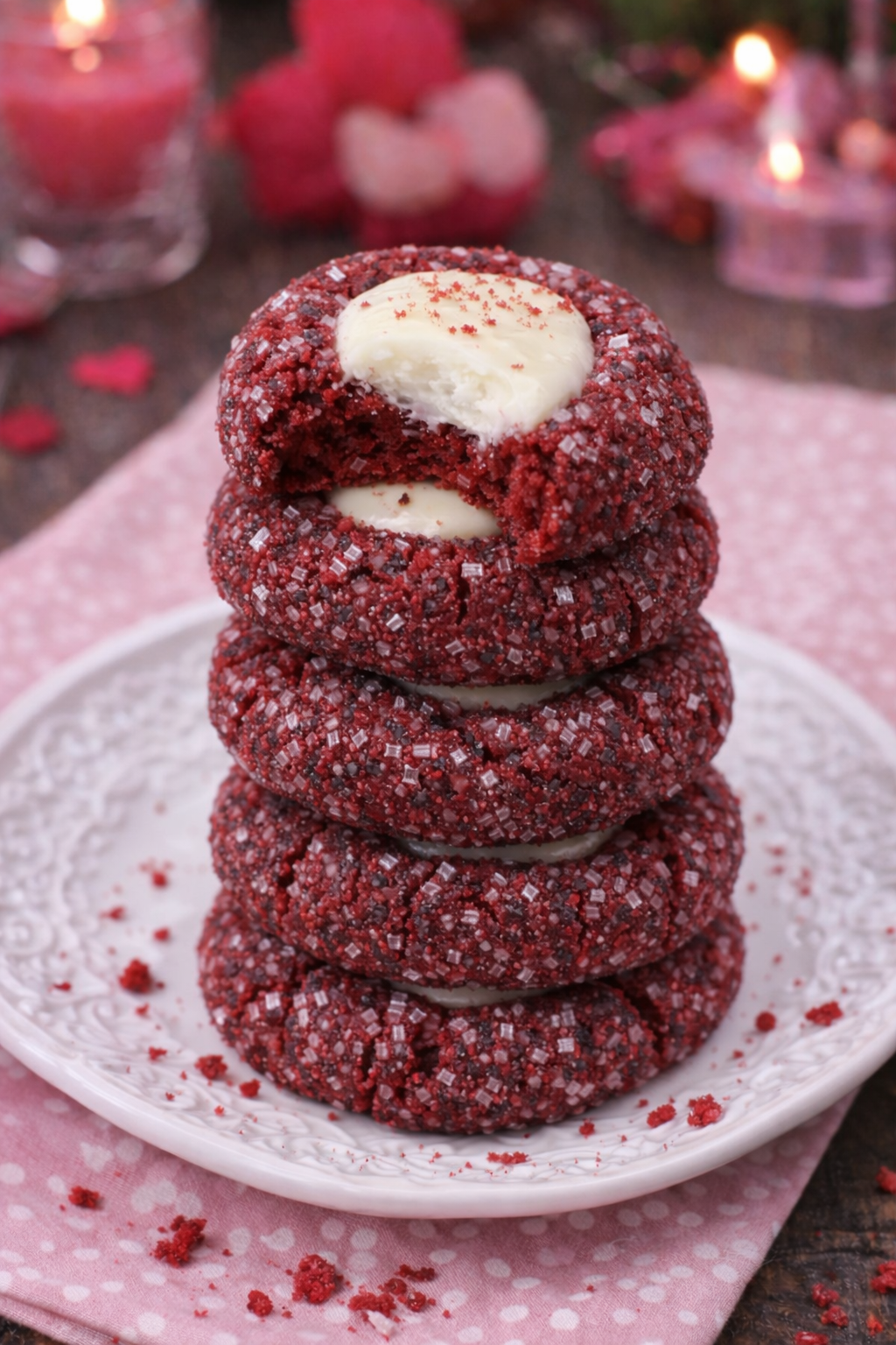 Red Velvet Cheesecake Thumbprint Cookies stacked on top of one another with a bite missing from the top one 