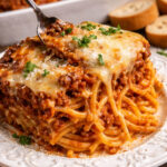 Cheesy Beefy Baked Spaghetti on a pretty white plate