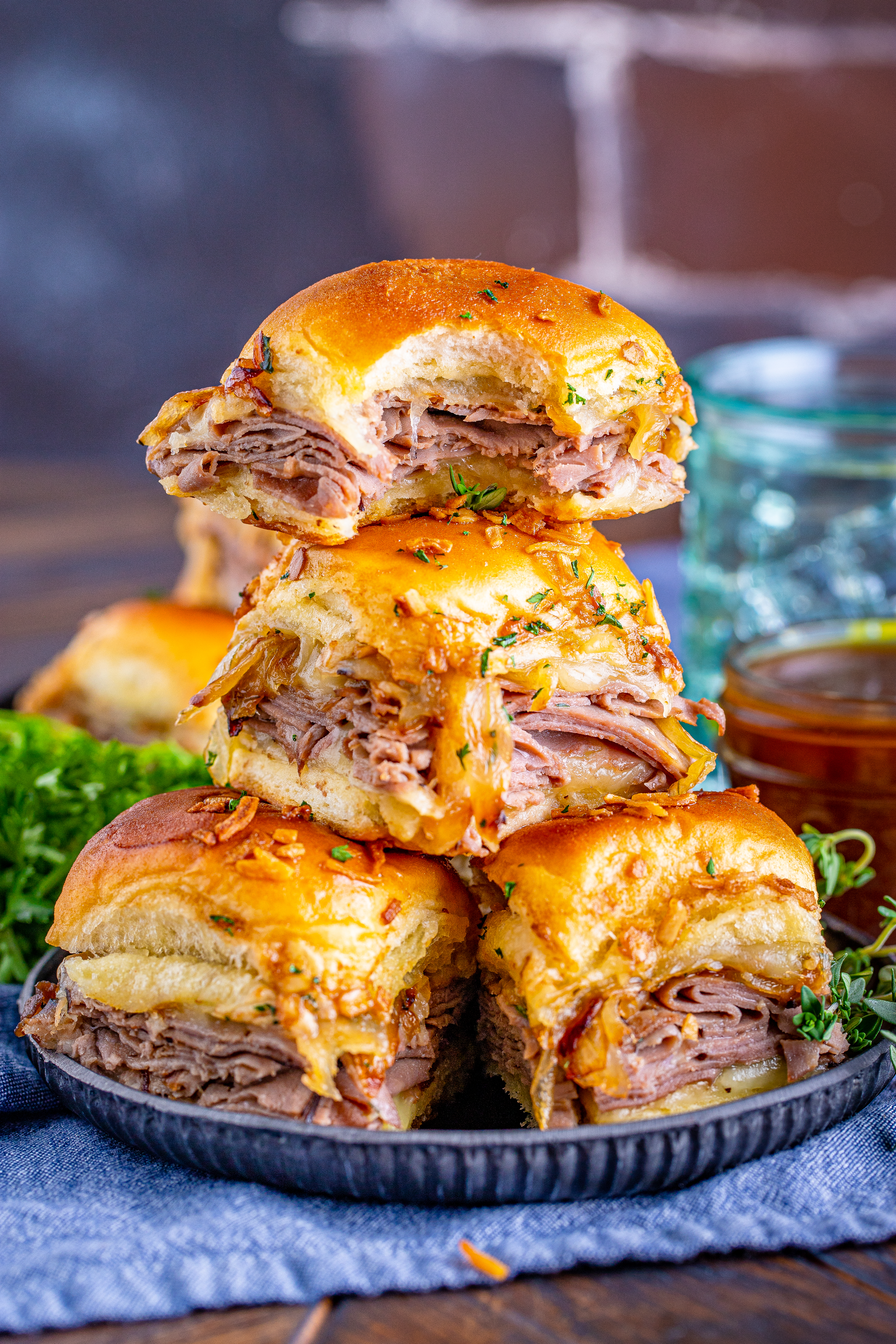 French Dip Sliders piled with the top having a bite taken on a black plate 