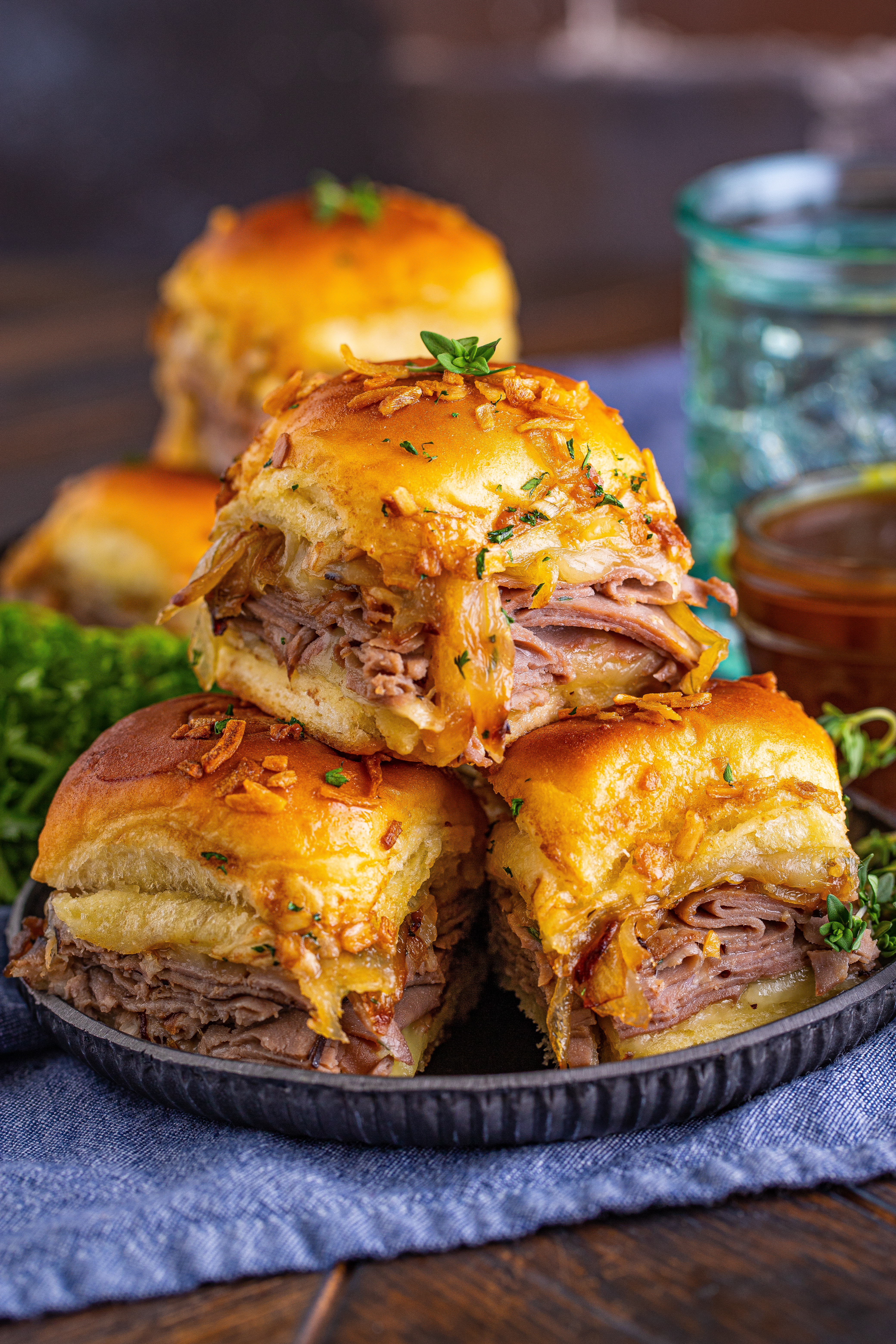 French Dip Sliders on a black plate piled 