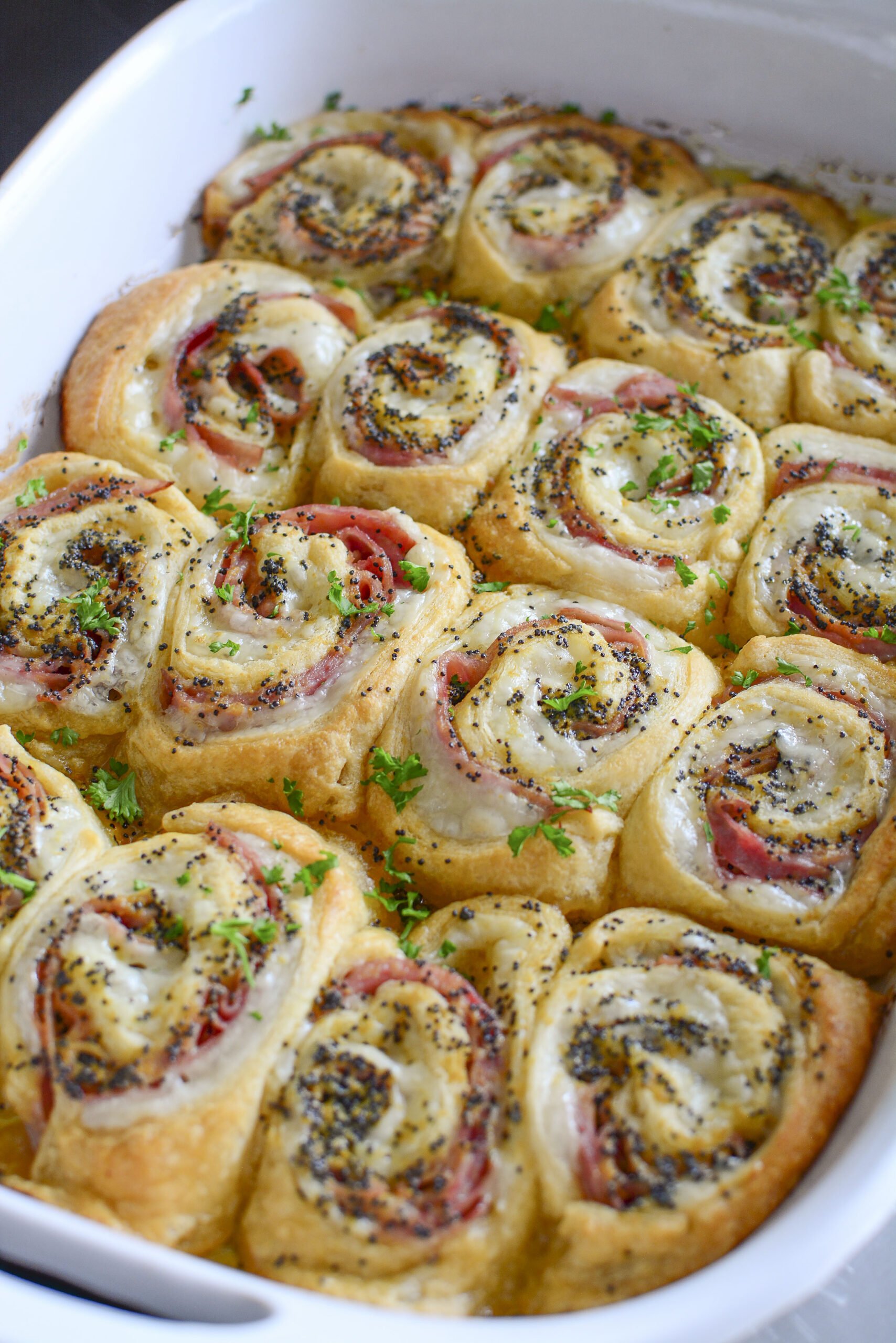 Ham and Cheese Pinwheels in a white baking dish side angle