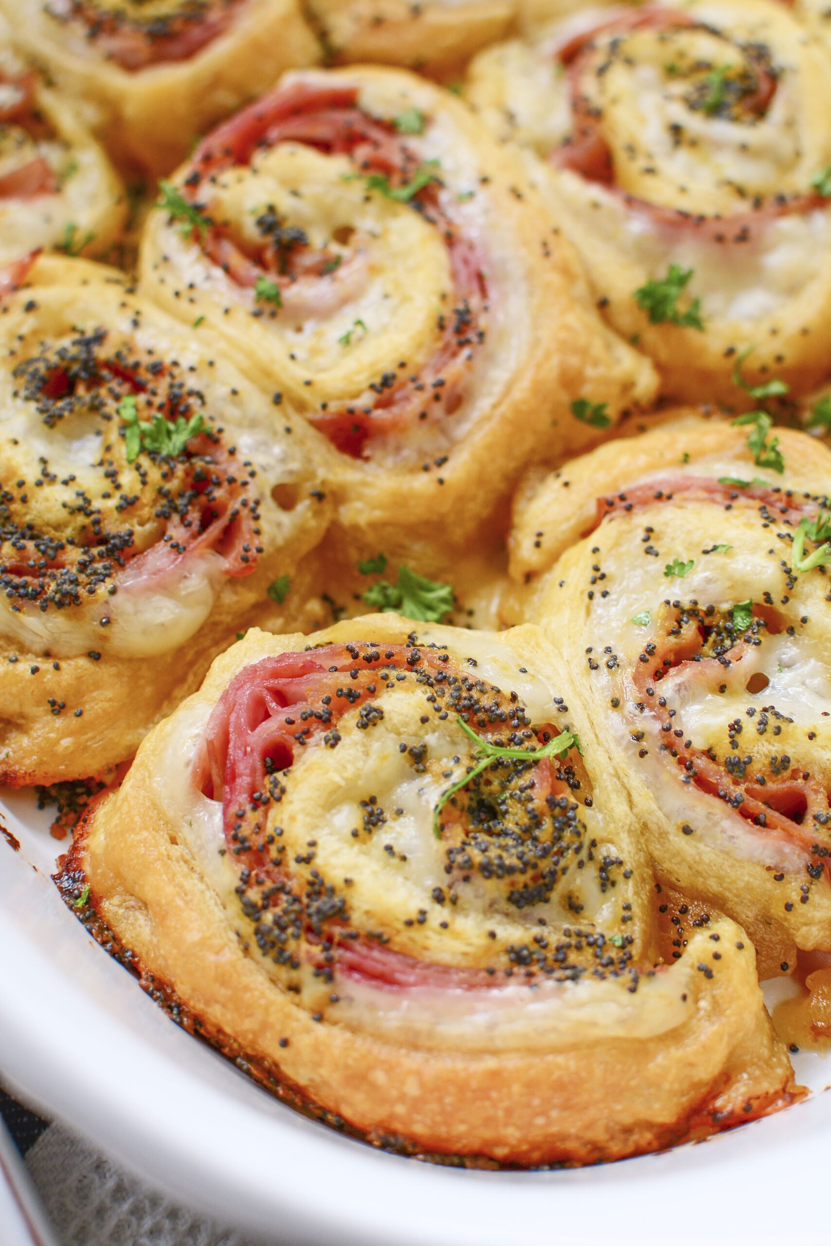 Ham and Cheese Pinwheels in a white baking dish side shot