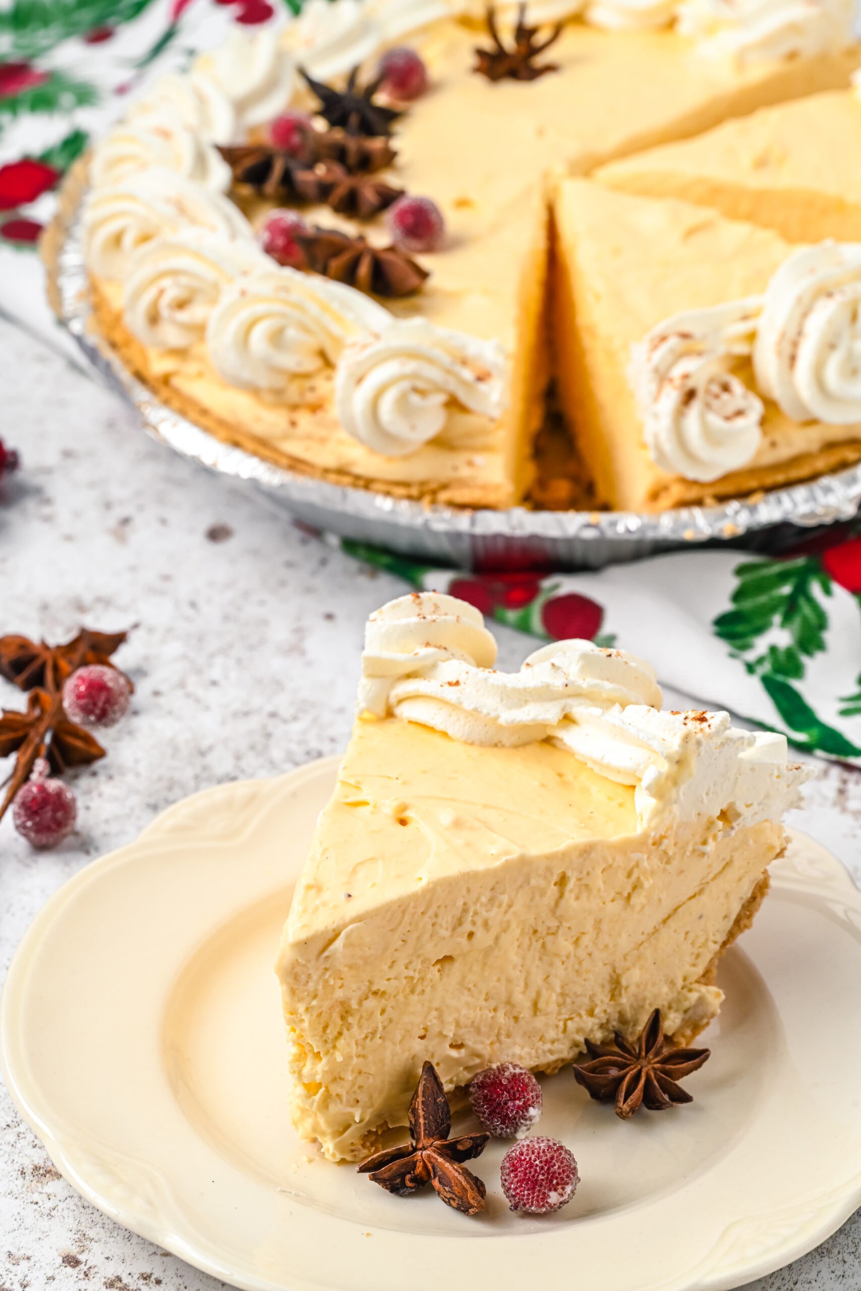 A piece of pie on a white dish with the full pie in the background. 