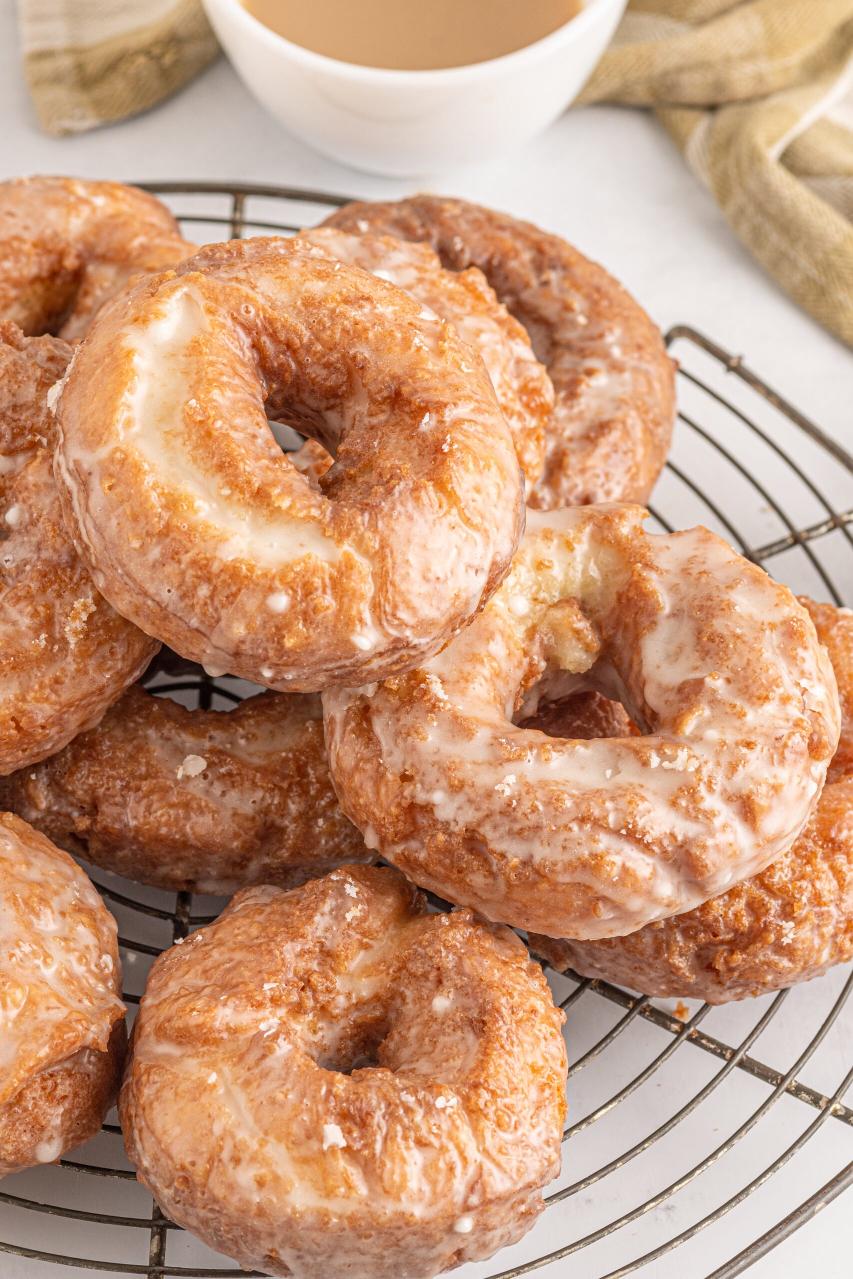 Side view of the donuts stacked on a wire cooling rack. 