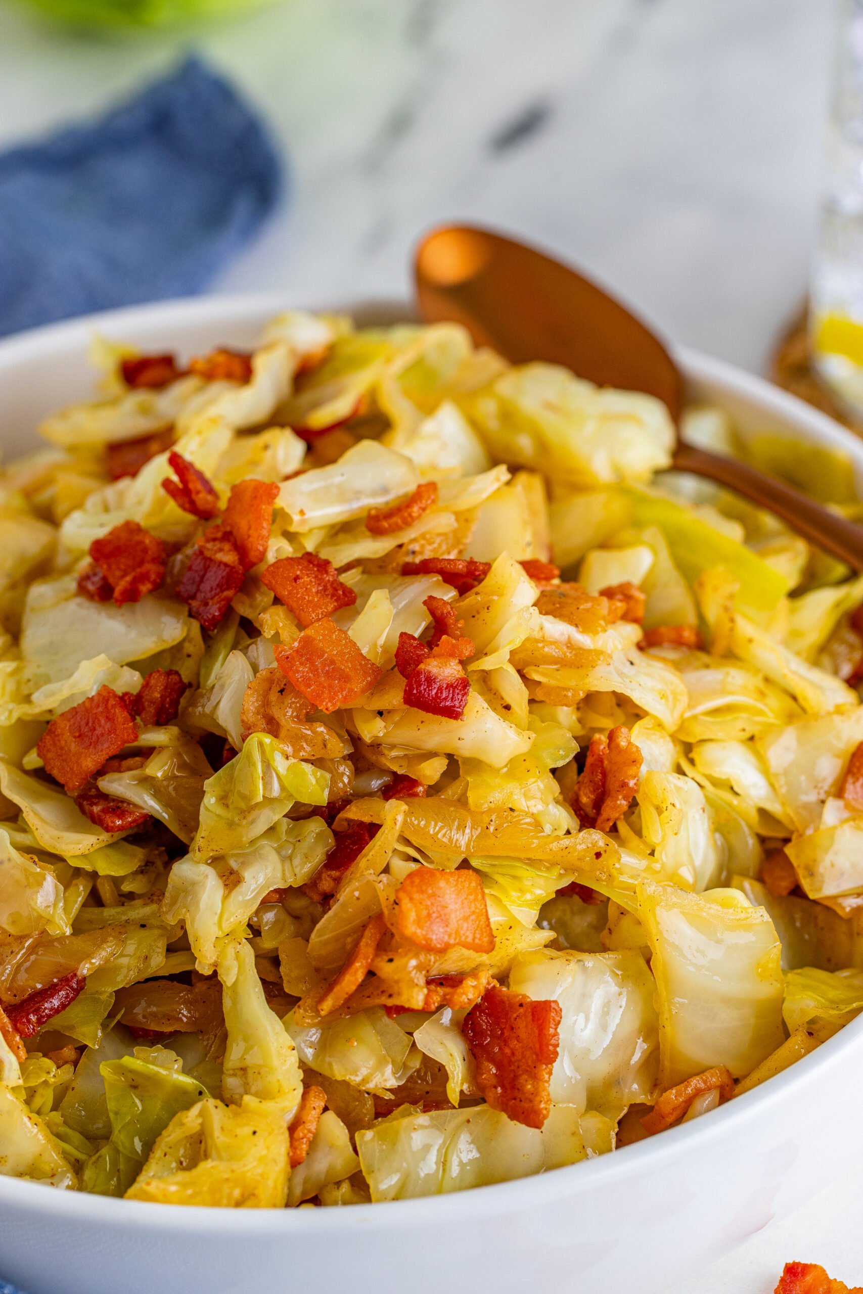 Fried Cabbage in a white bowl with a gold spoon. 