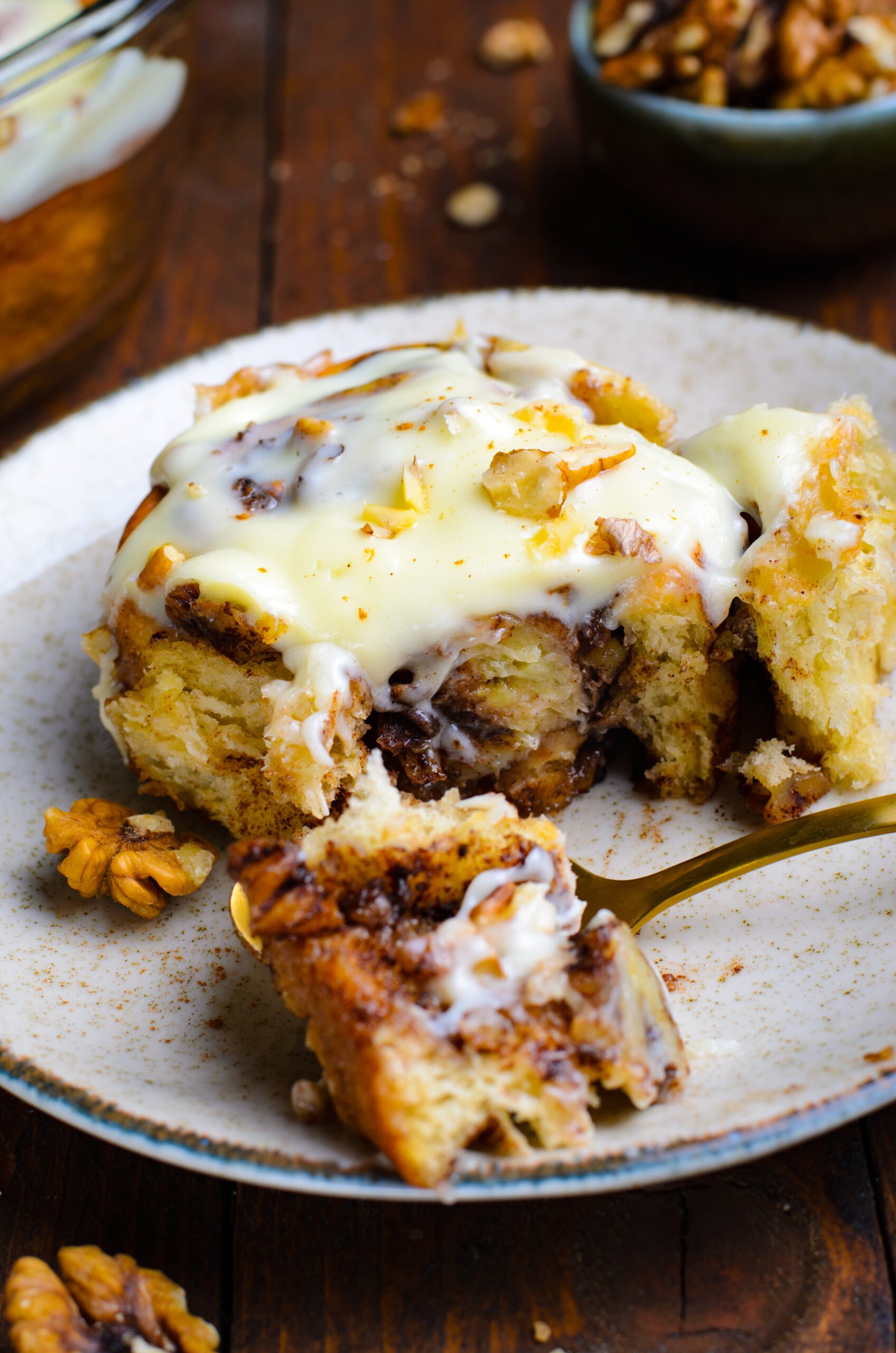 Banana nut cinnamon roll on a white plate cut open with a bite taken out 