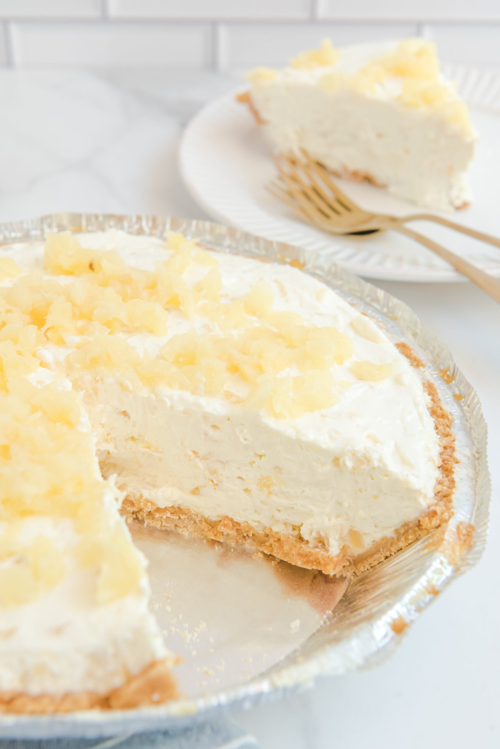 No Bake Pineapple Cheesecake Pie in a pie plate with a  slice removed