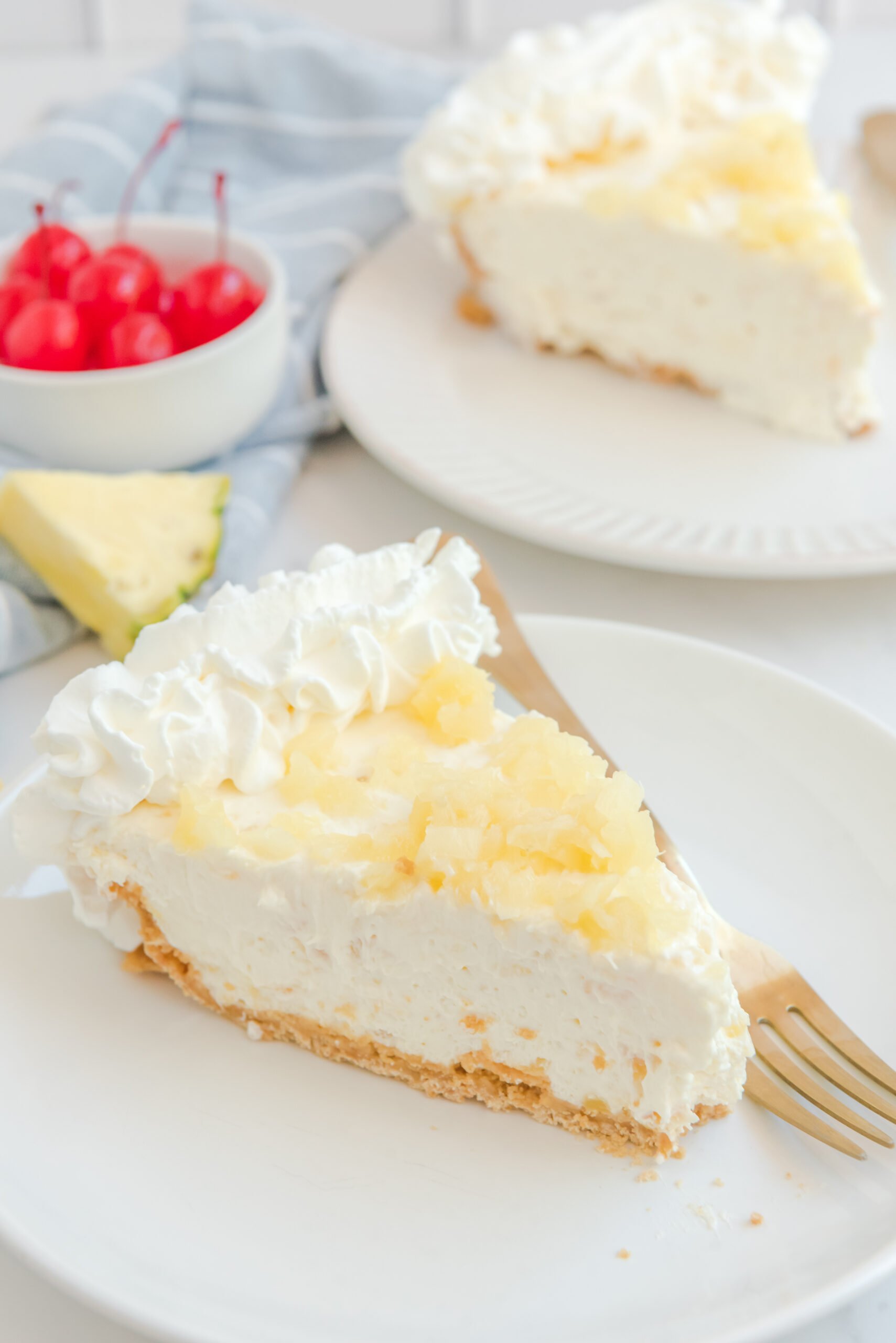 a slice of No Bake Pineapple Cheesecake Pie on a white plate topped with pineapple 