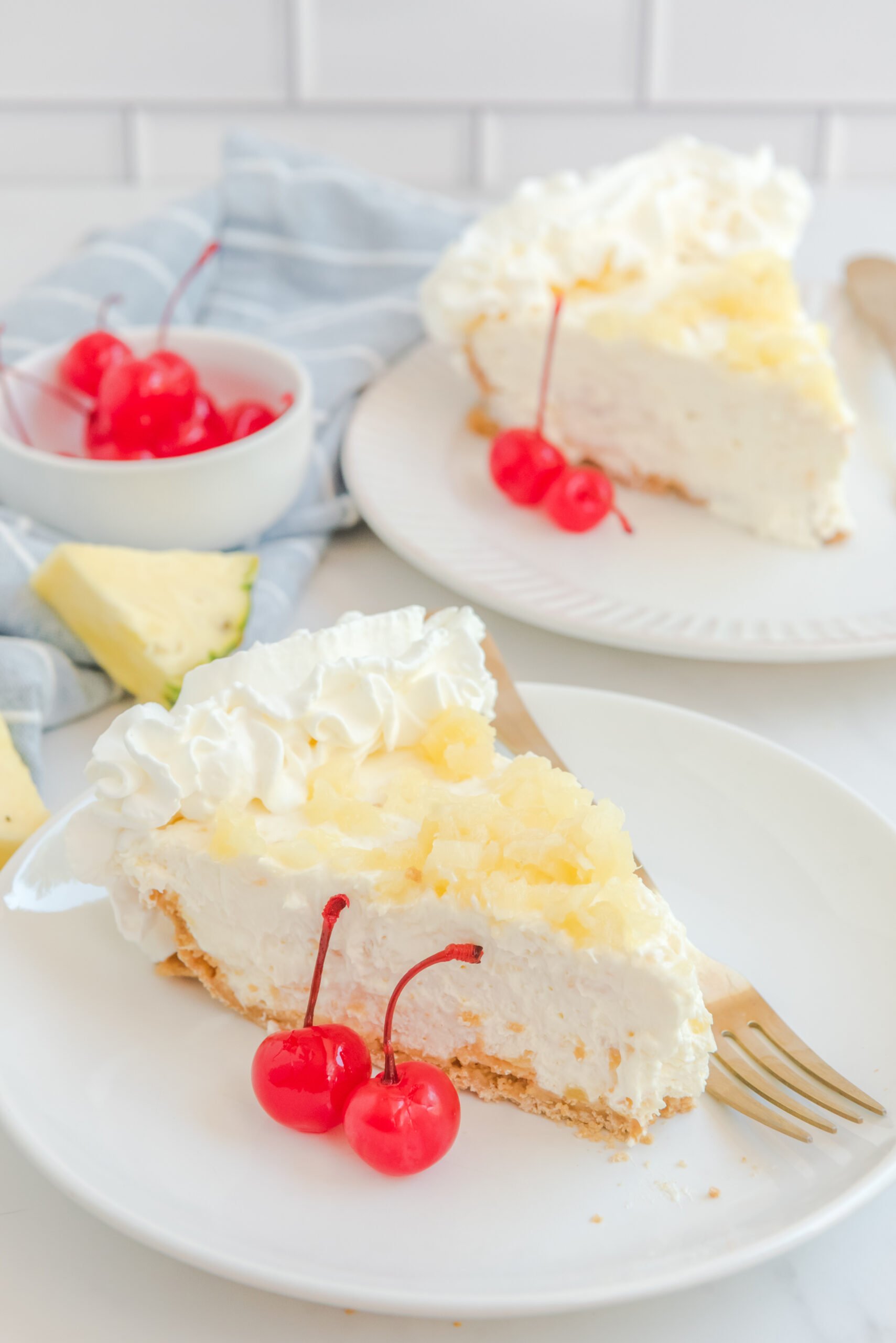No Bake Pineapple Cheesecake Pie on a white plate with maraschino cherries next to a slice