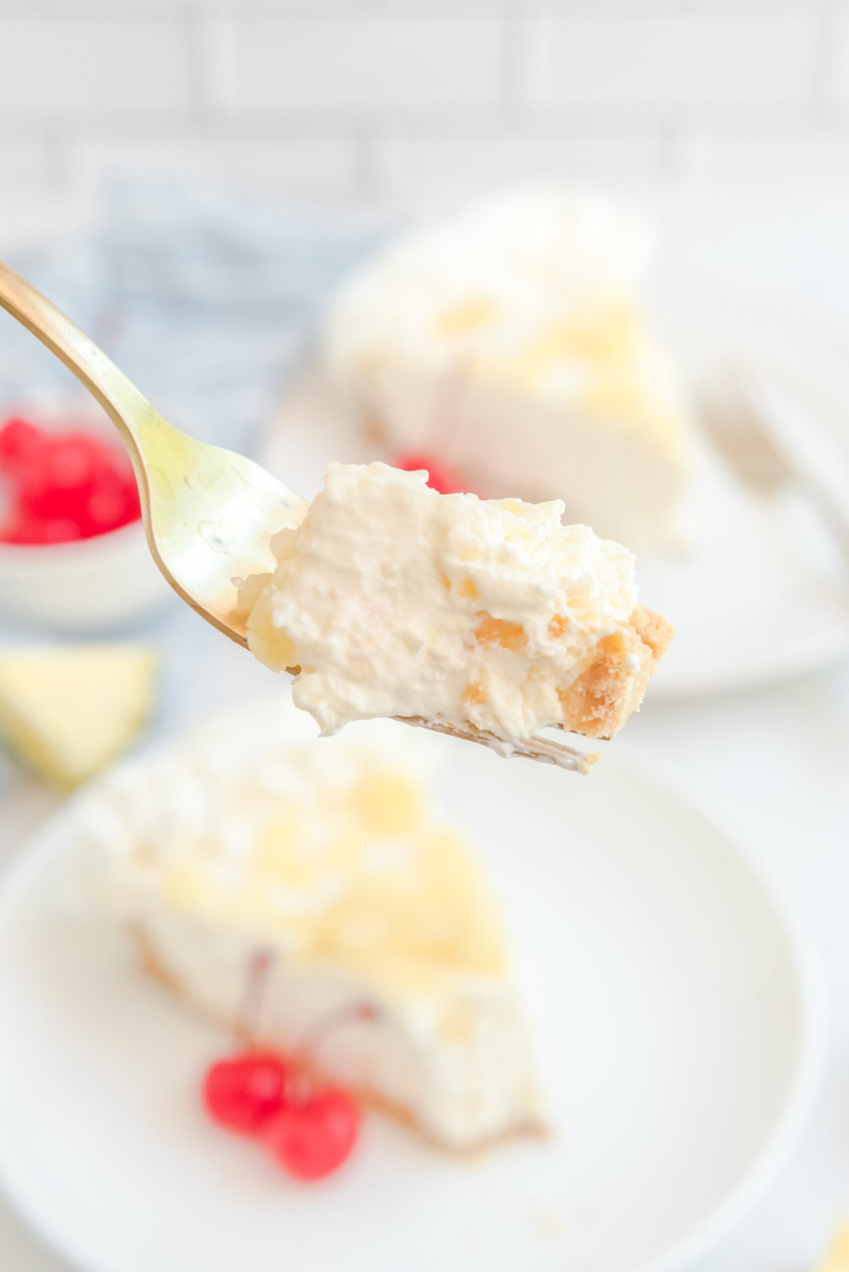 Up close view of a bite of No Bake Pineapple Cheesecake on a gold fork.