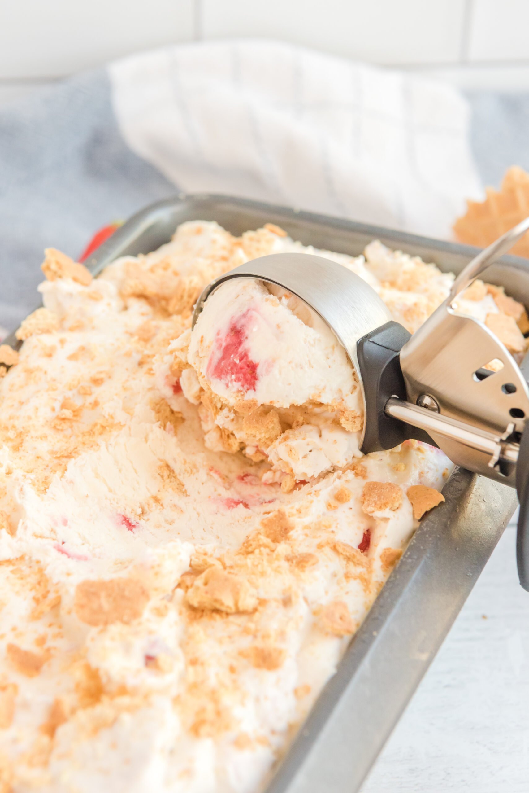 Close up view of an ice cream scoop scooping Strawberry Cheesecake Ice Cream.
