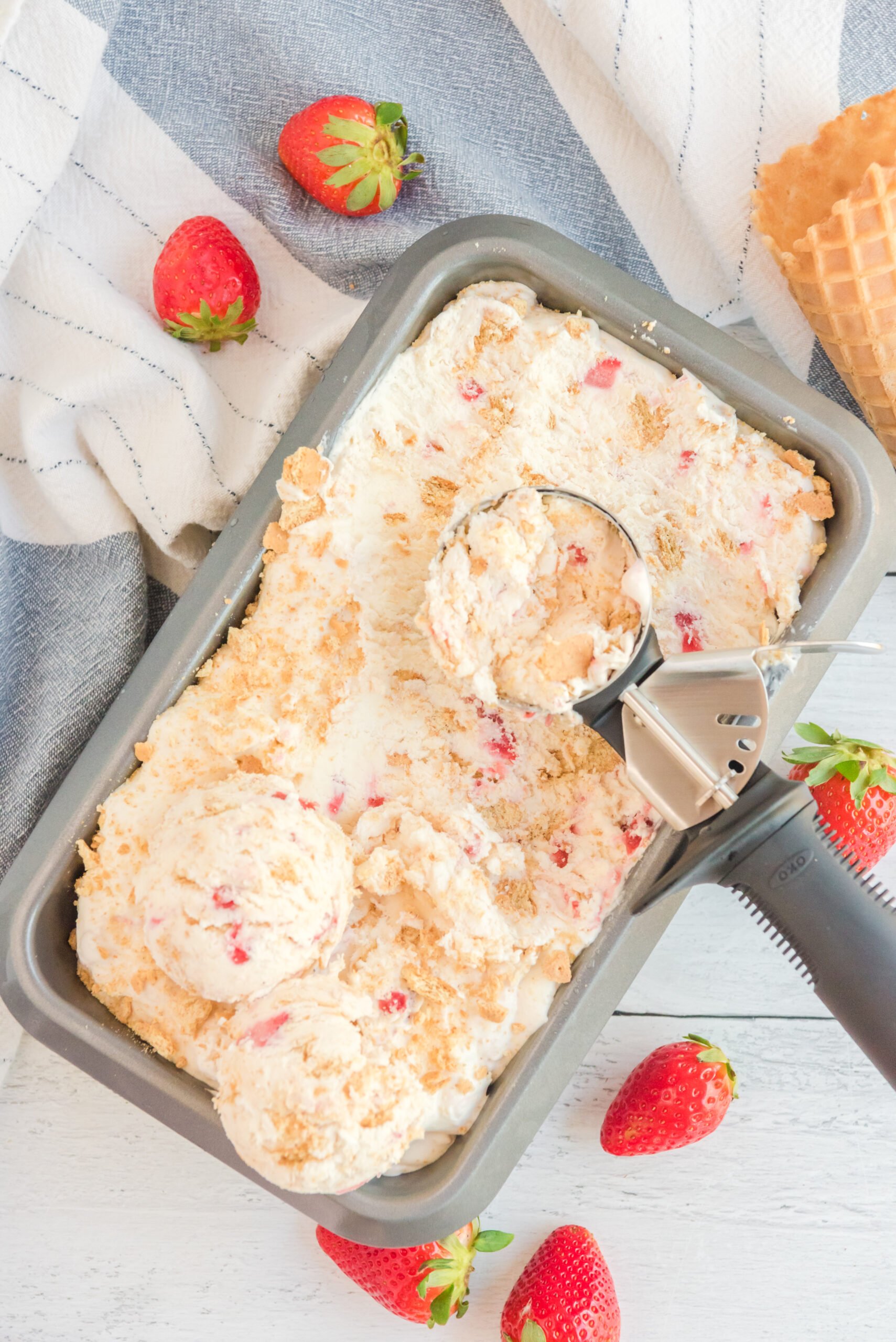 overhead shot view of an ice cream scoop scooping Strawberry Cheesecake Ice Cream.