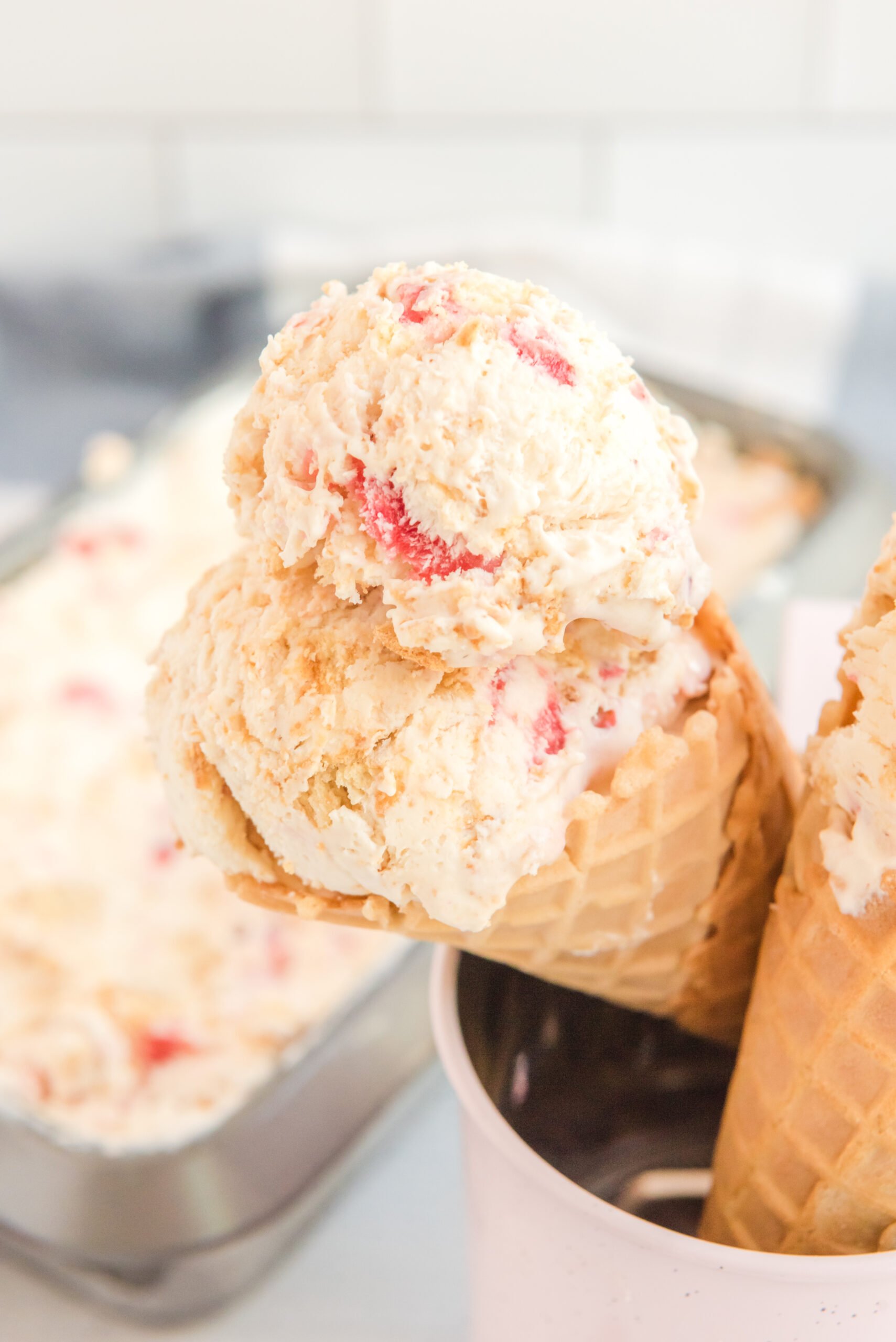 Up close view of a waffle cone with a scoop of Strawberry Cheesecake Ice Cream.