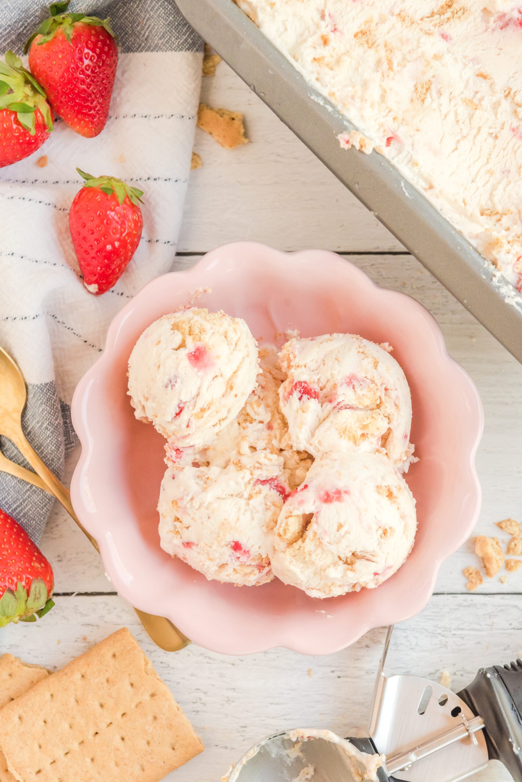 Overhead view of scoops of Strawberry Cheesecake Ice Cream in a pink bowl.