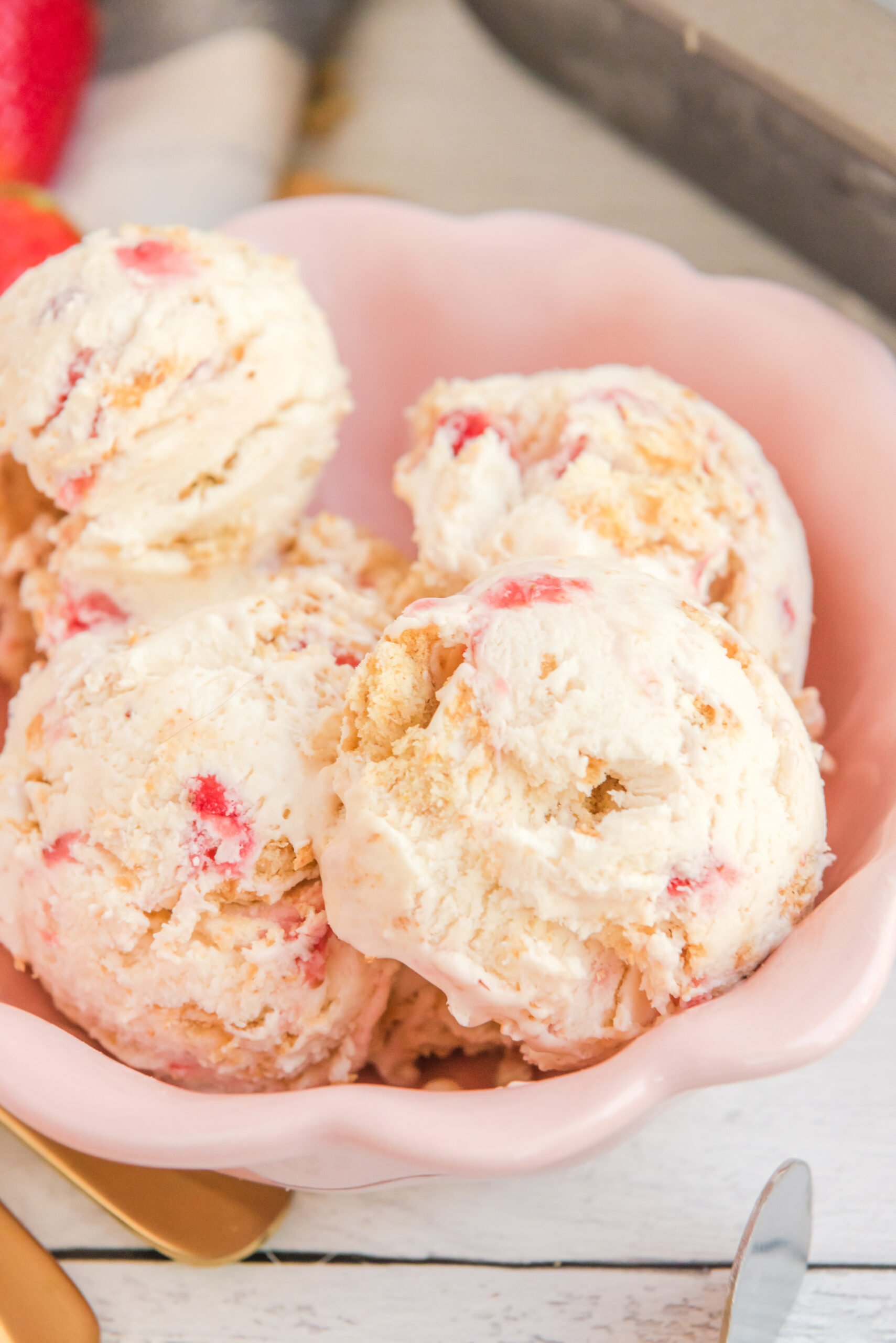 Close up view of scoops of Strawberry Cheesecake Ice Cream in a pink bowl.