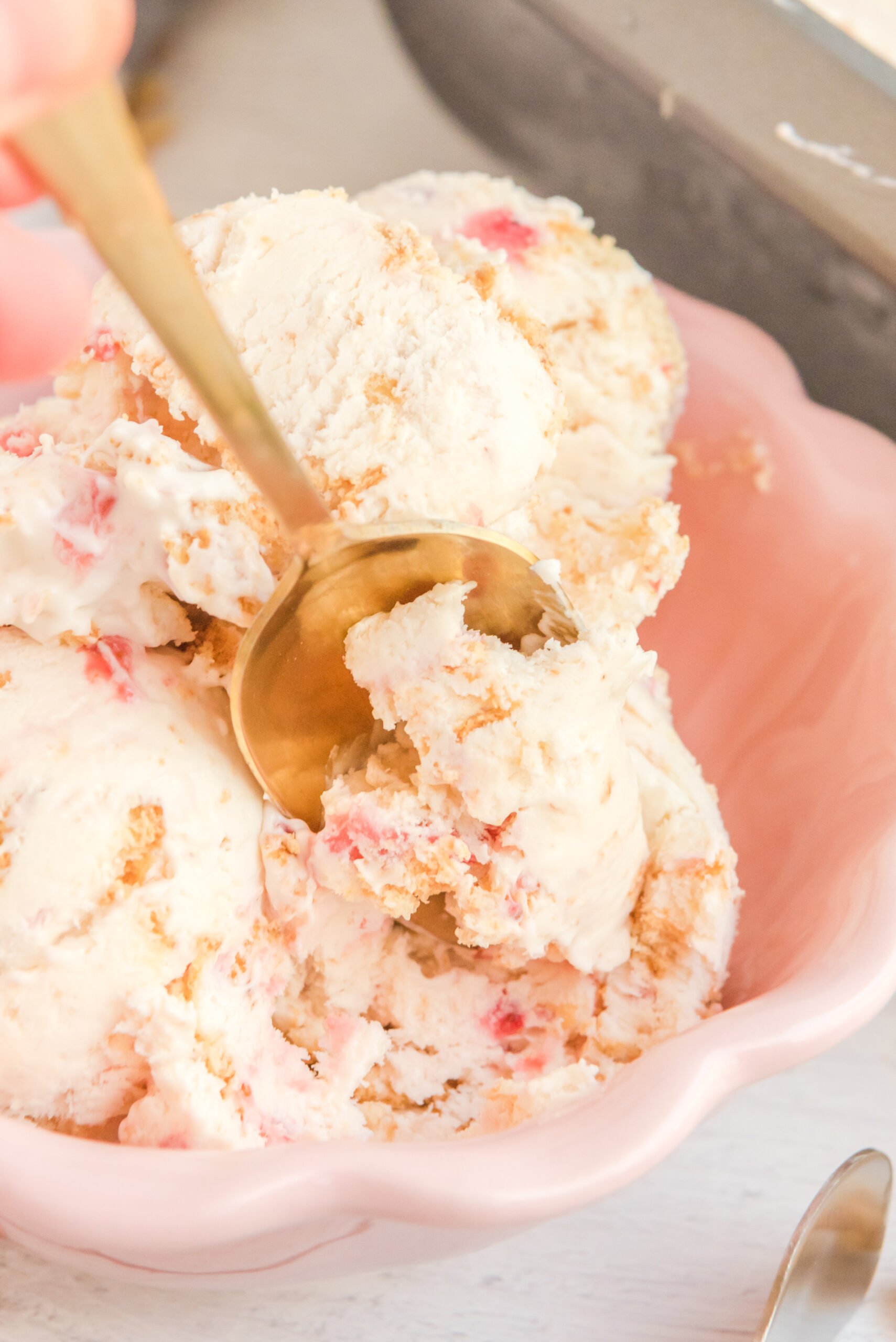 Close up view of a gold spoon removing a bite of Strawberry Cheesecake Ice Cream.