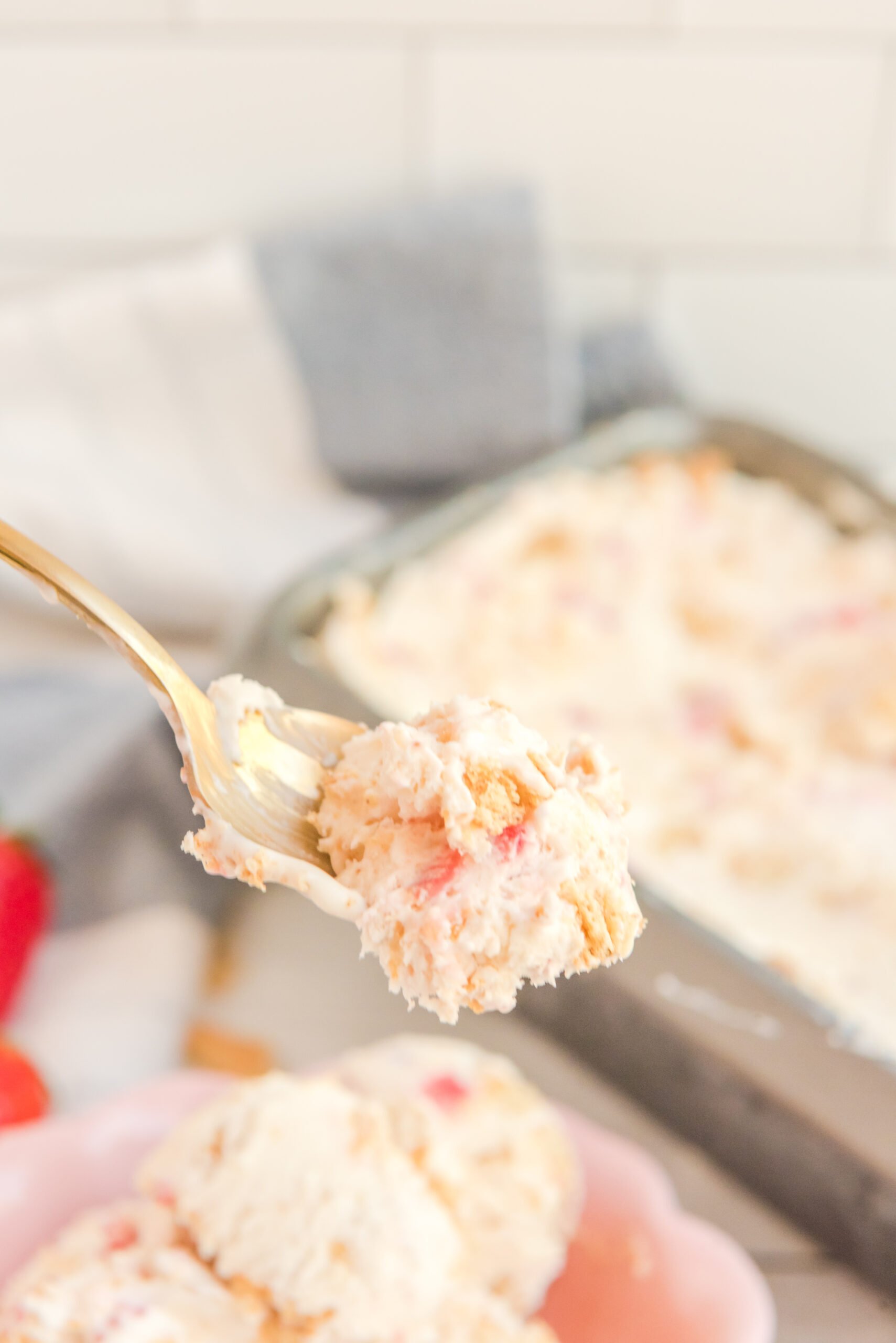 Front view of a bite of Strawberry Cheesecake Ice Cream on a gold spoon.