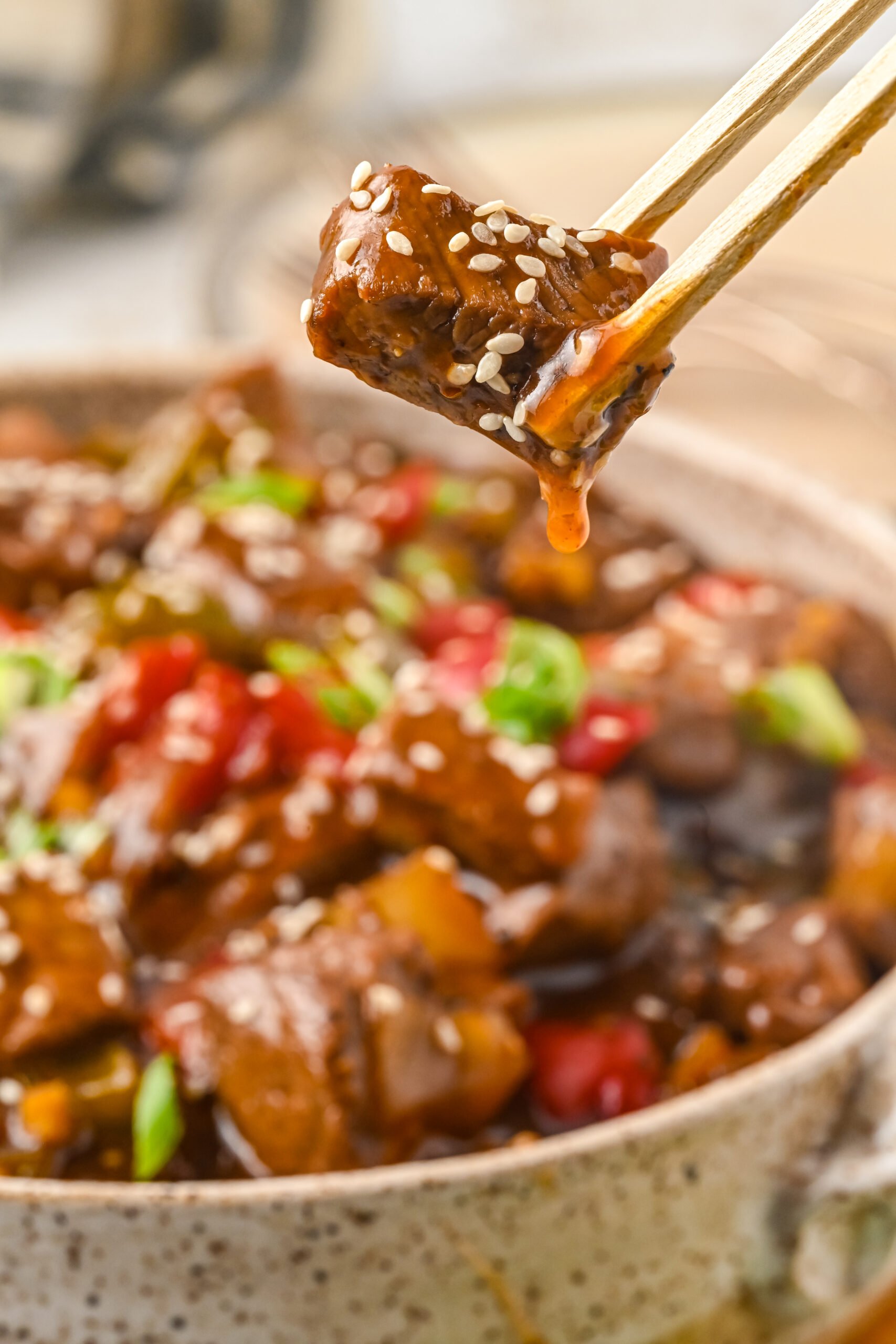 Close up view of chopsticks holding a piece of Chinese Pepper Steak.