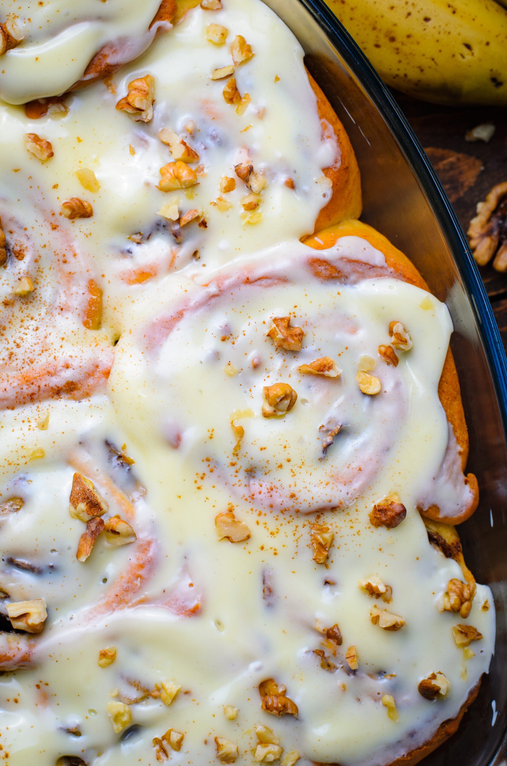 Close up view of Banana Nut Cinnamon Rolls in a clear baking dish.