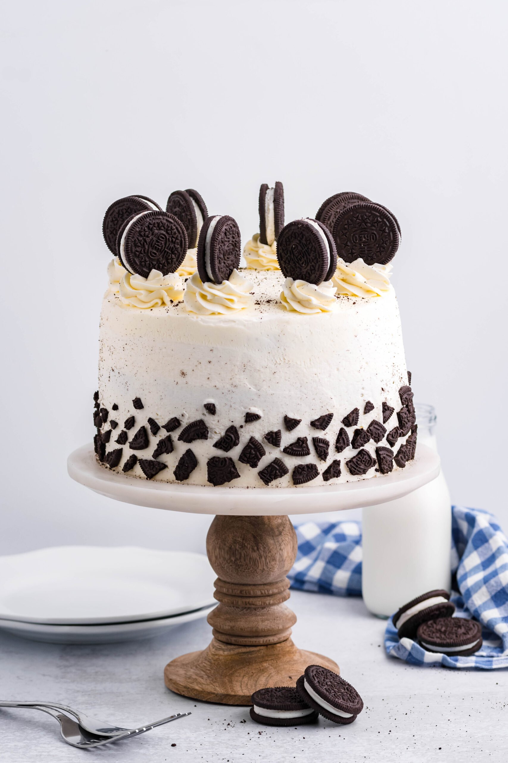 Front view of Double Stuffed Oreo Cake on a white and wooden cake stand.