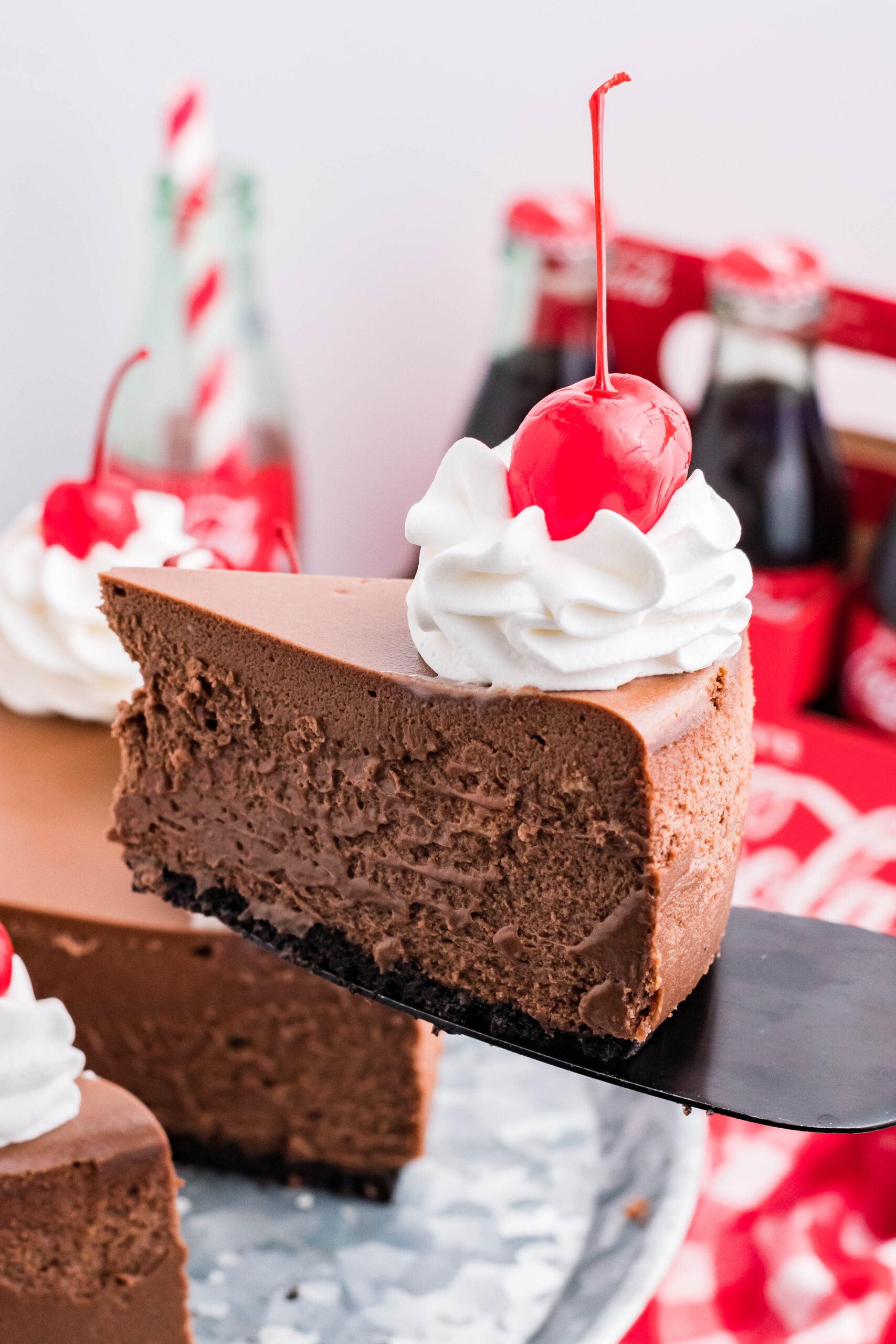 Side view of a slice of Coca Cola Cheesecake on a black cake server.