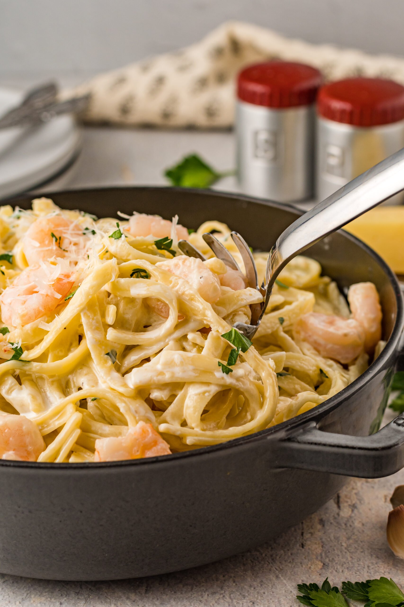 Front view of a silver serving spoon scooping out Shrimp Alfredo.