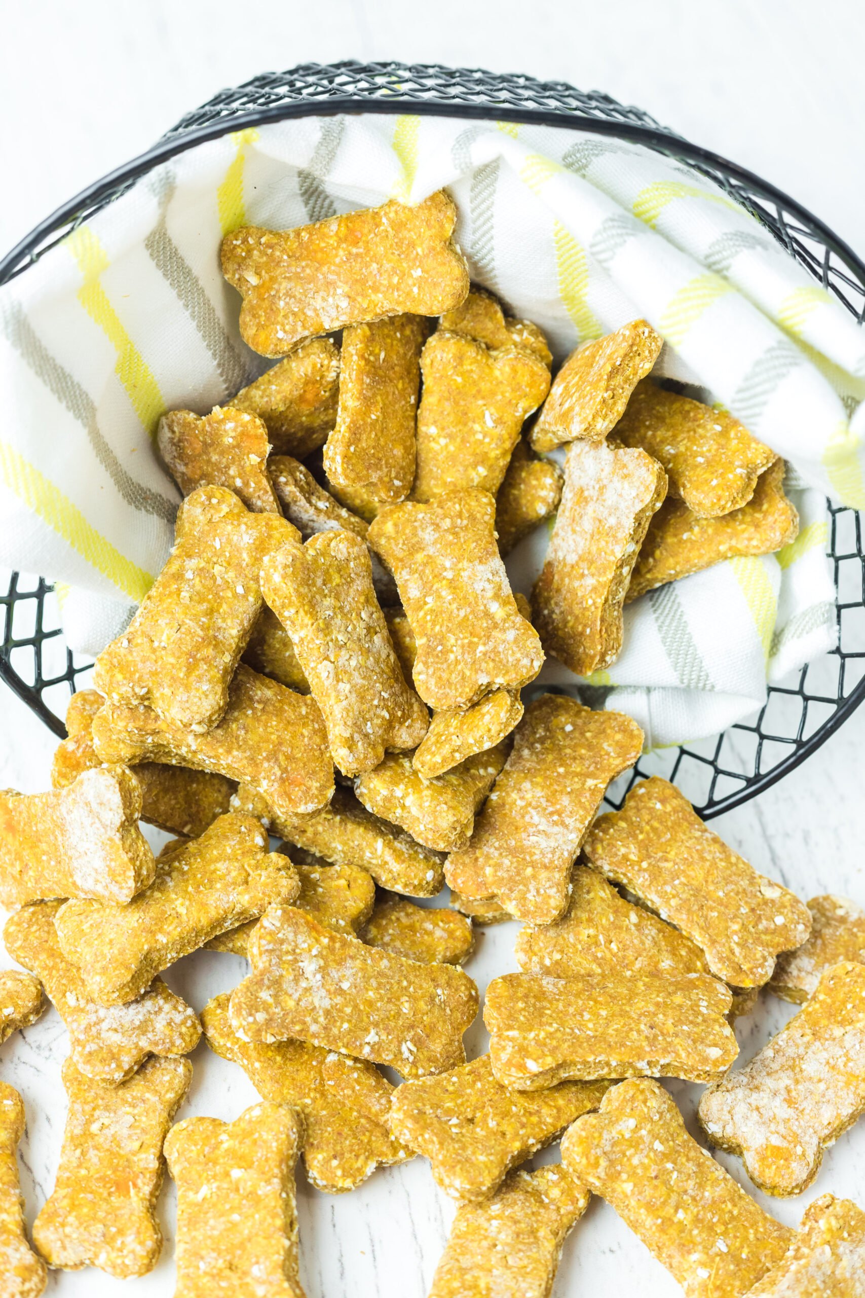 Front view of Sweet Potato and Pumpkin Dog Treats spilling out of a wire basket lined with linen.