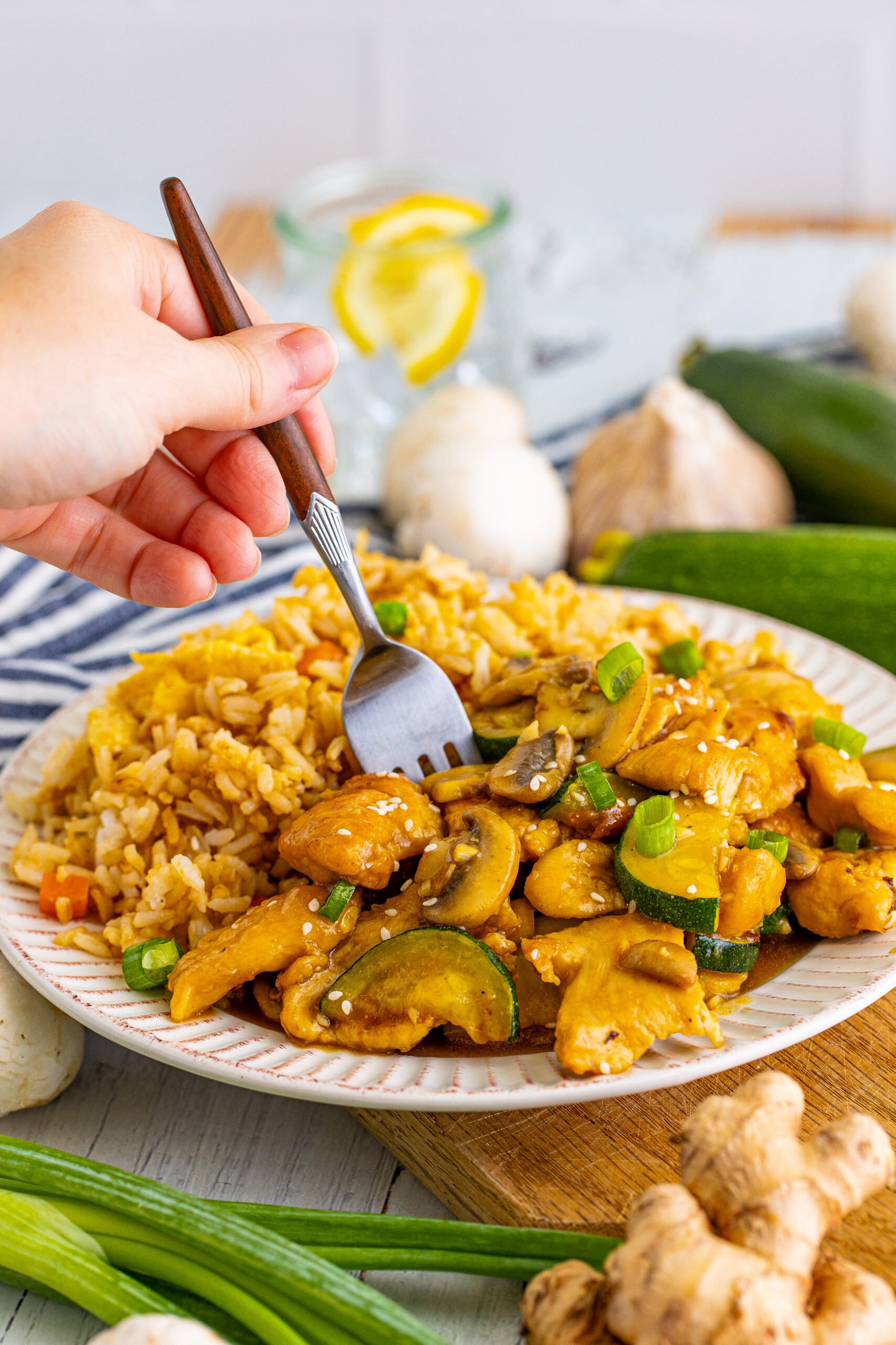Front view of Panda Express Mushroom Chicken on a white dish served with fried rice with a silver fork.