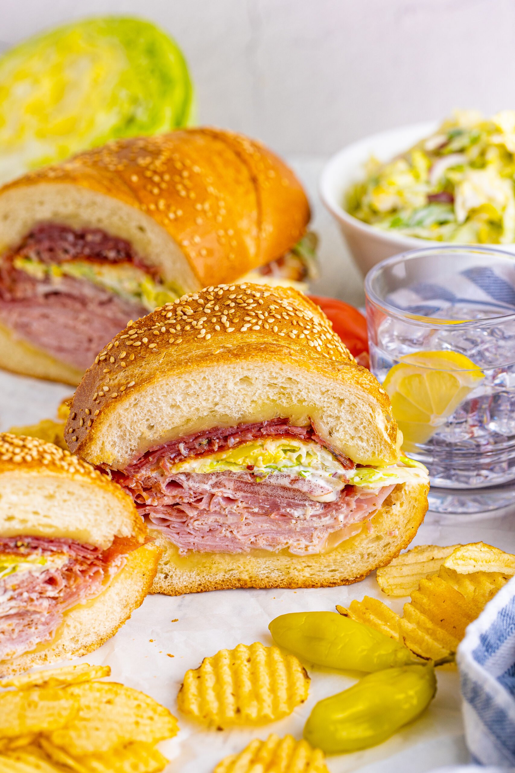 Front view of Grinder Subs on parchment paper surrounded by wavy chips.