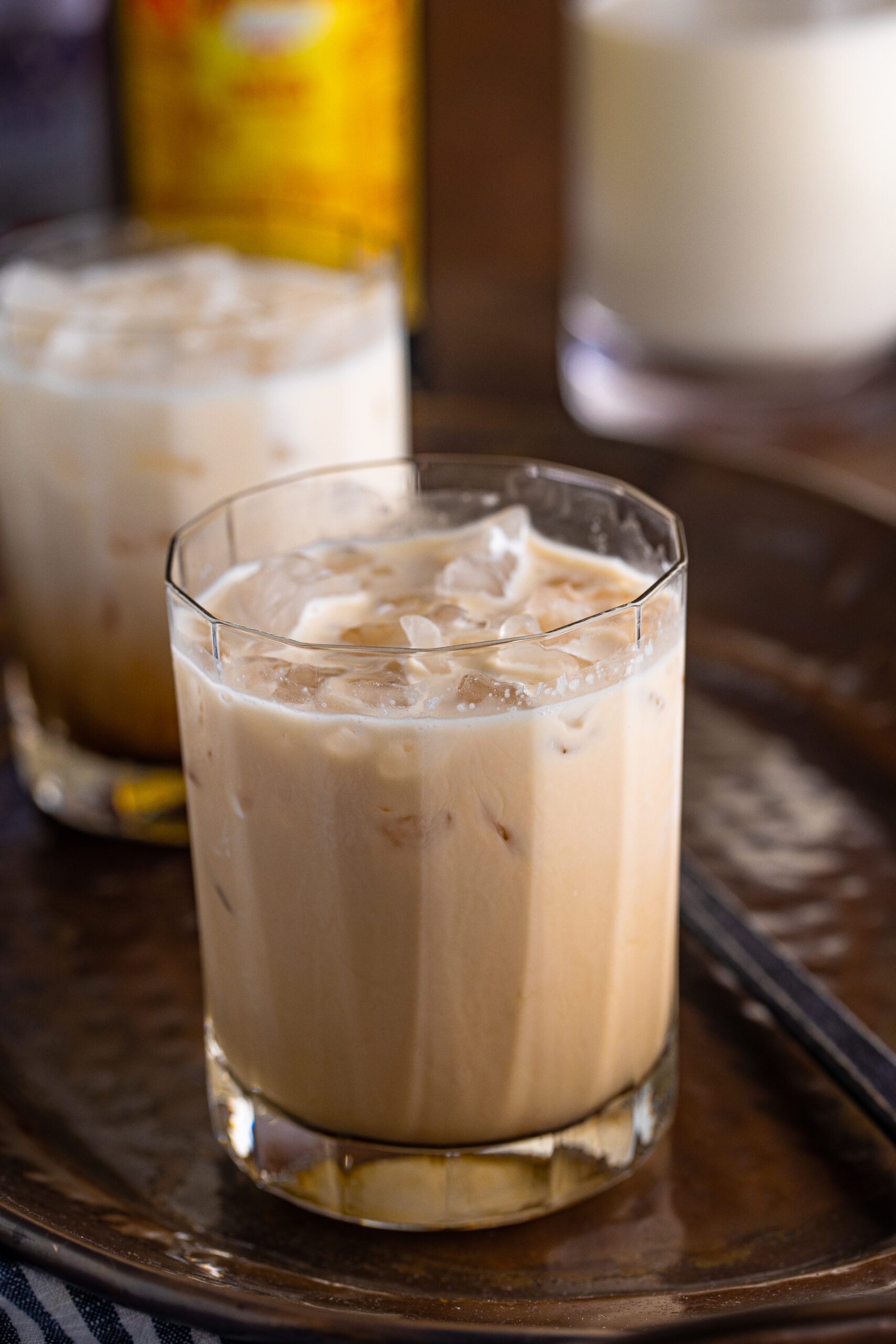 White Russian in a clear glass sitting on a dark metal serving tray.