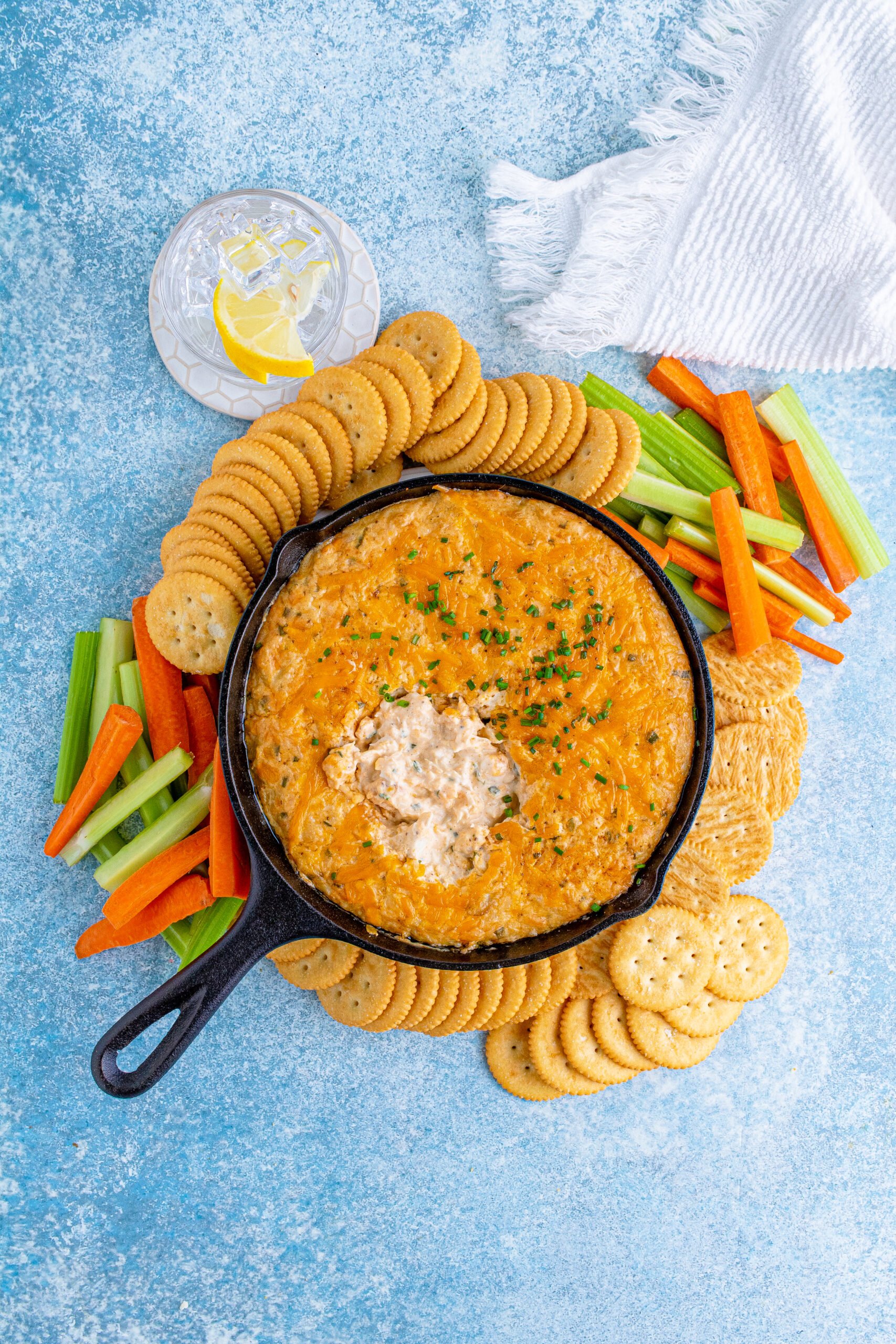 Overhead view of Crab Dip Recipe in a cast iron skillet served with crackers and vegetables.
