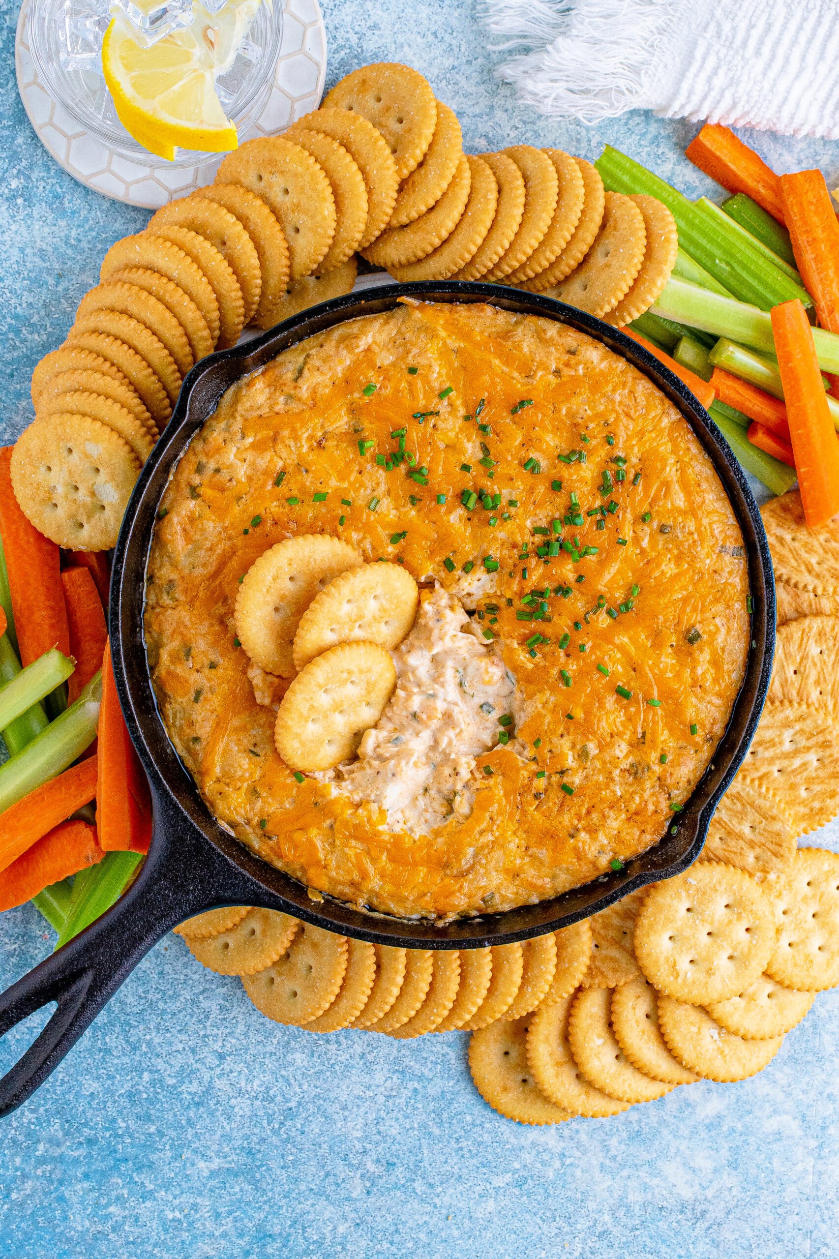 Overhead view of Crab Dip Recipe in a cast iron skillet served with crackers and vegetables.