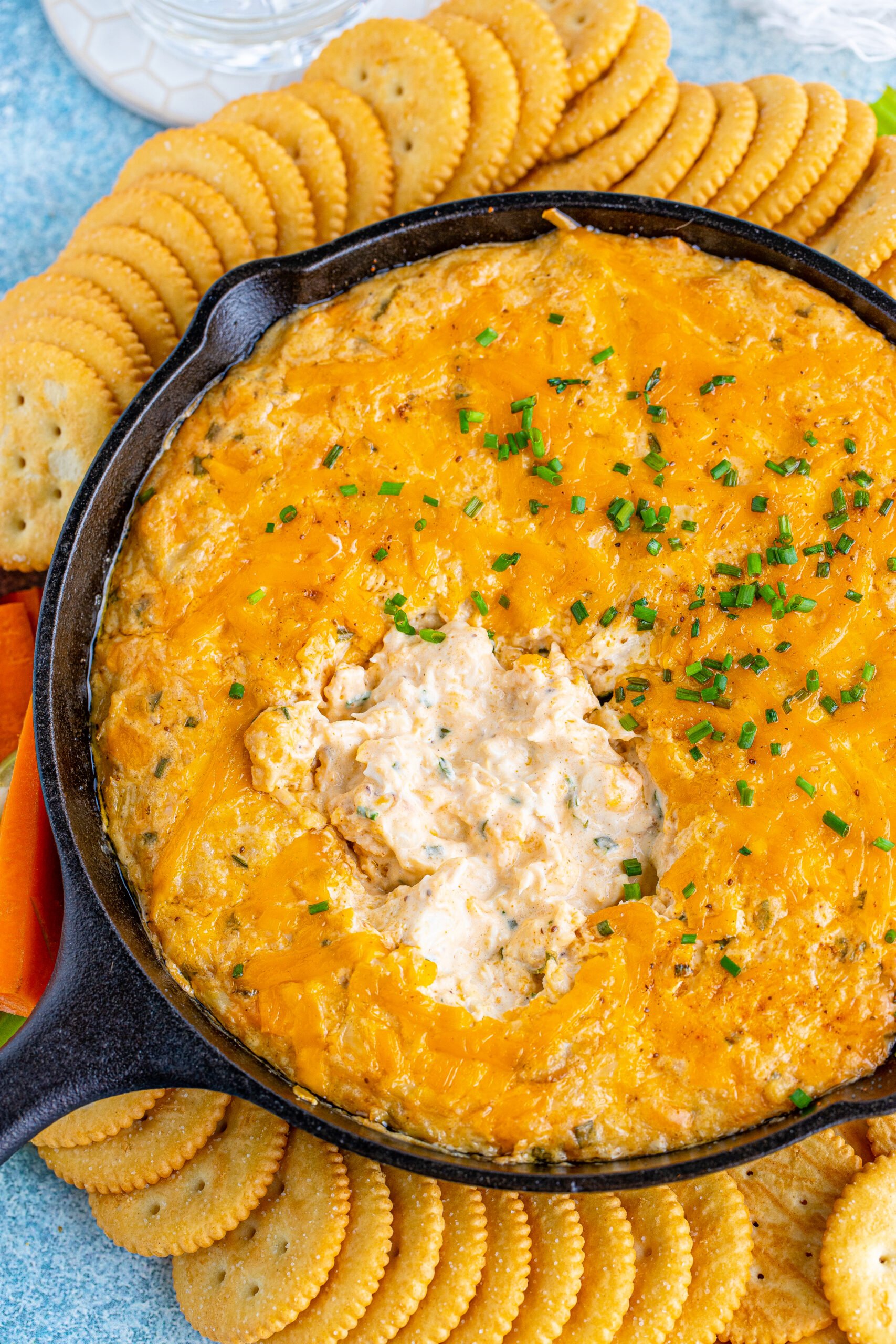 Overhead view of Crab Dip Recipe in a cast iron skillet served with crackers and vegetables.