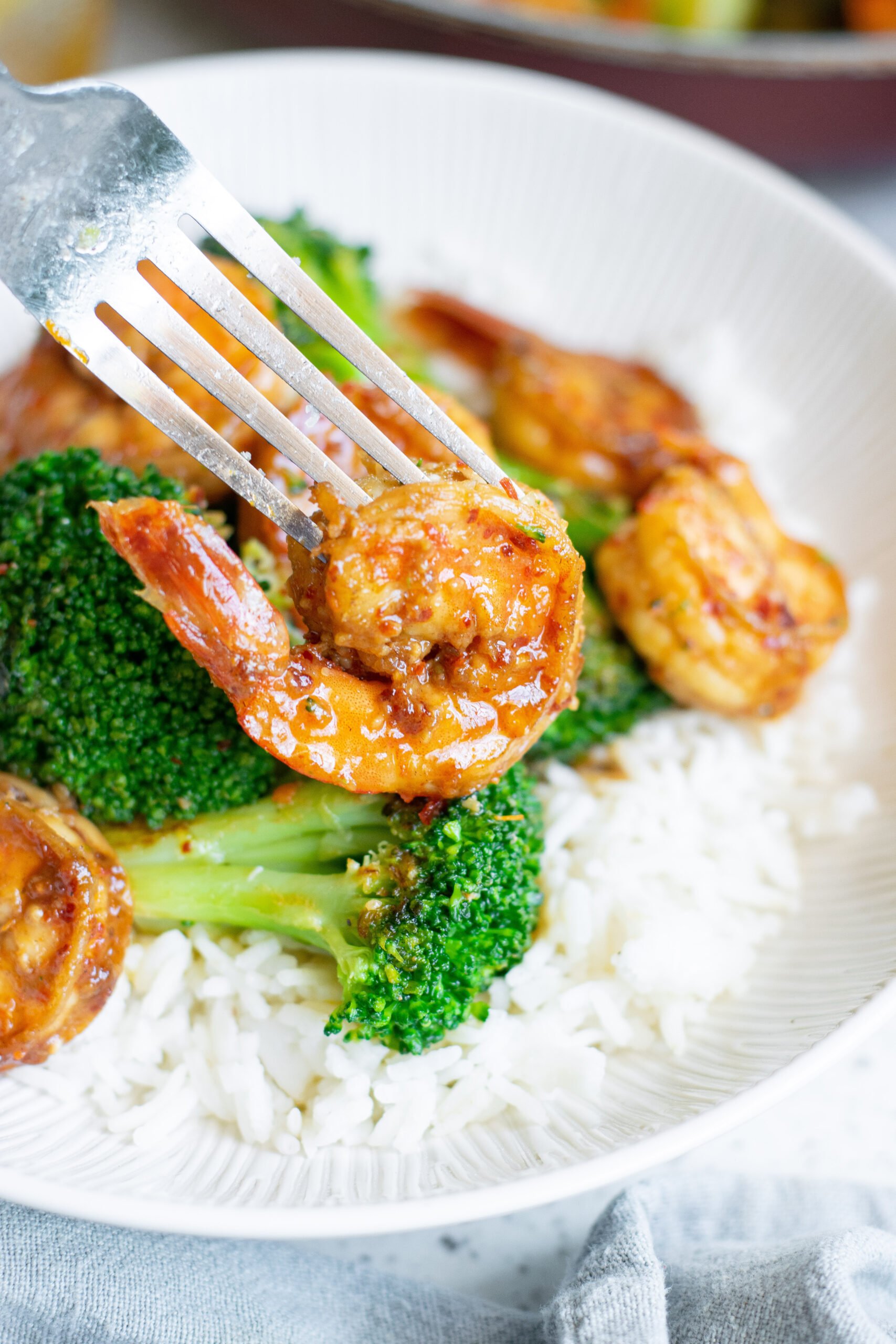 Up close view of a fork removing a shrimp from the plate. 