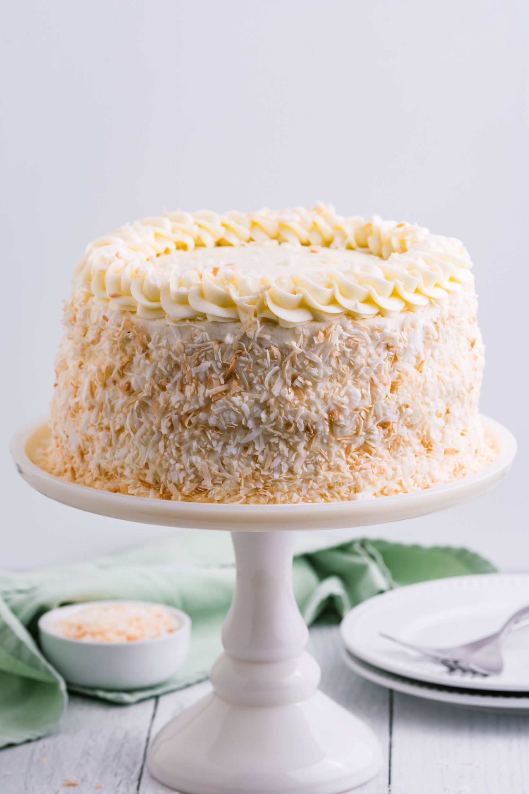 Front view of Coconut Custard Cake on a white cake stand.
