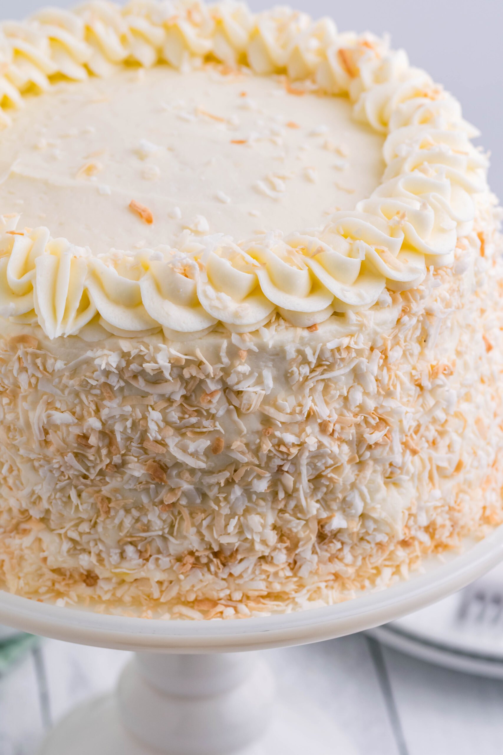 Close up view of Coconut Custard Cake on a white cake stand.