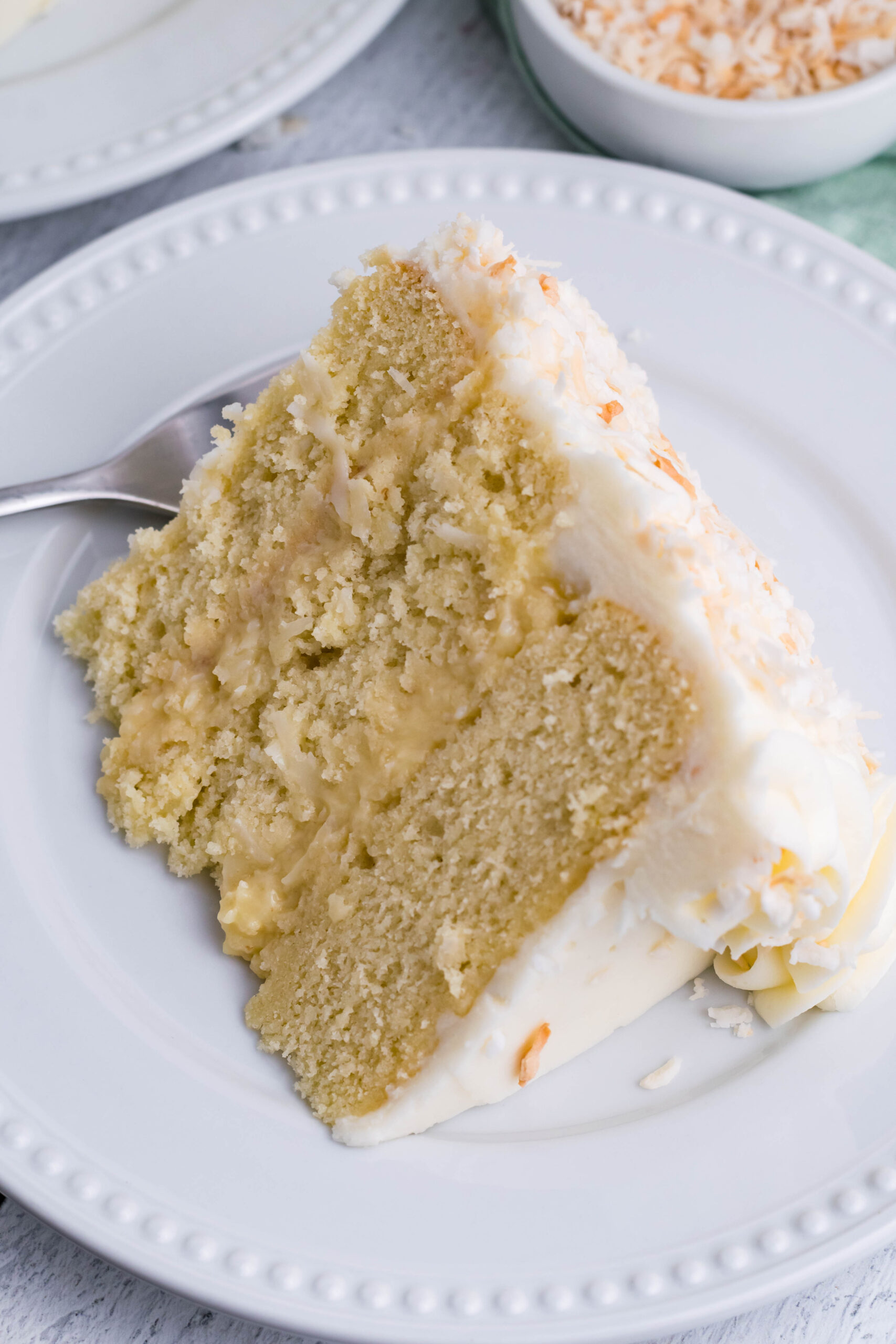 Close up view of a slice of Coconut Custard Cake on a white plate.