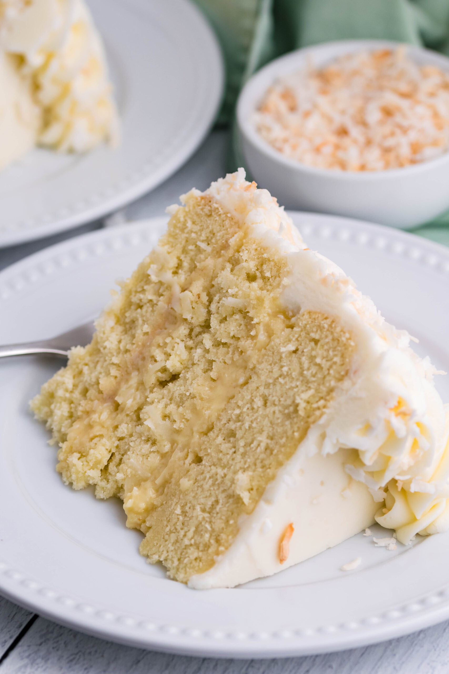 Front view of a slice of Coconut Custard Cake on a white plate.