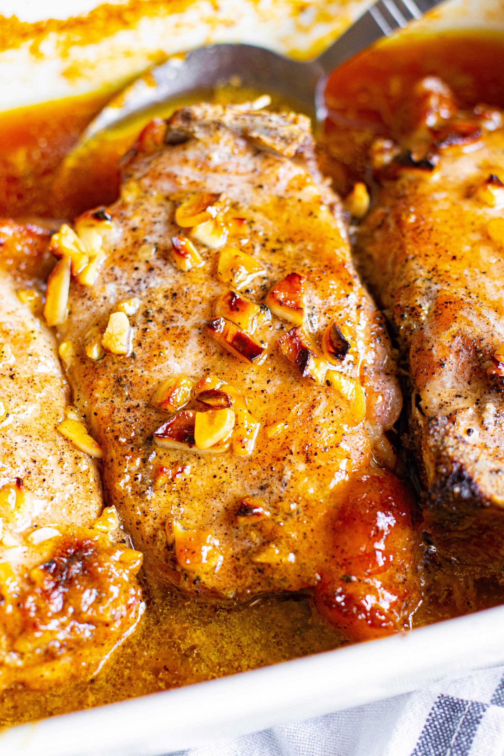 Close up view of Honey Garlic Pork Chops in a white baking dish.