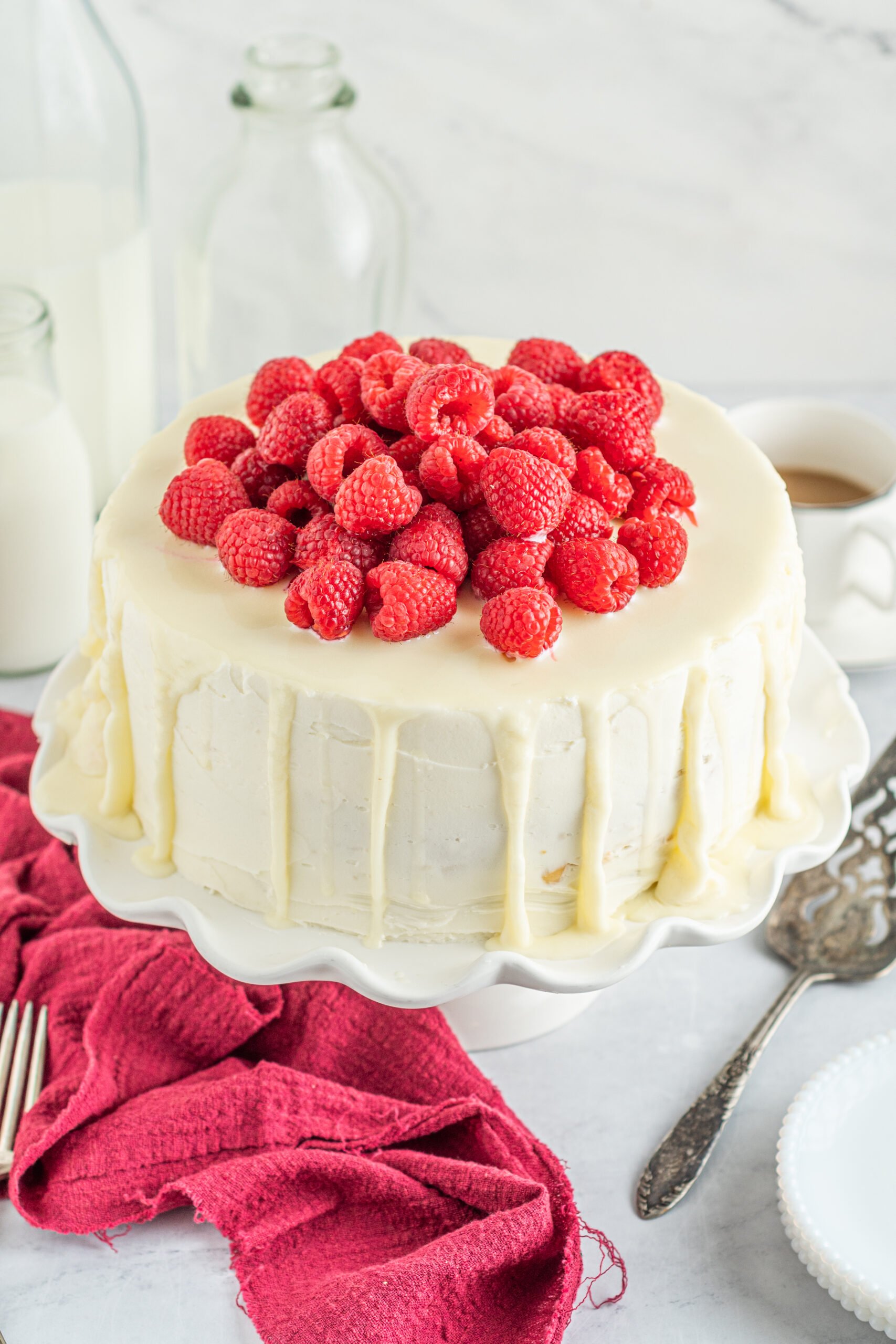 Front view of White Chocolate Cake with Raspberries on a white cake stand.