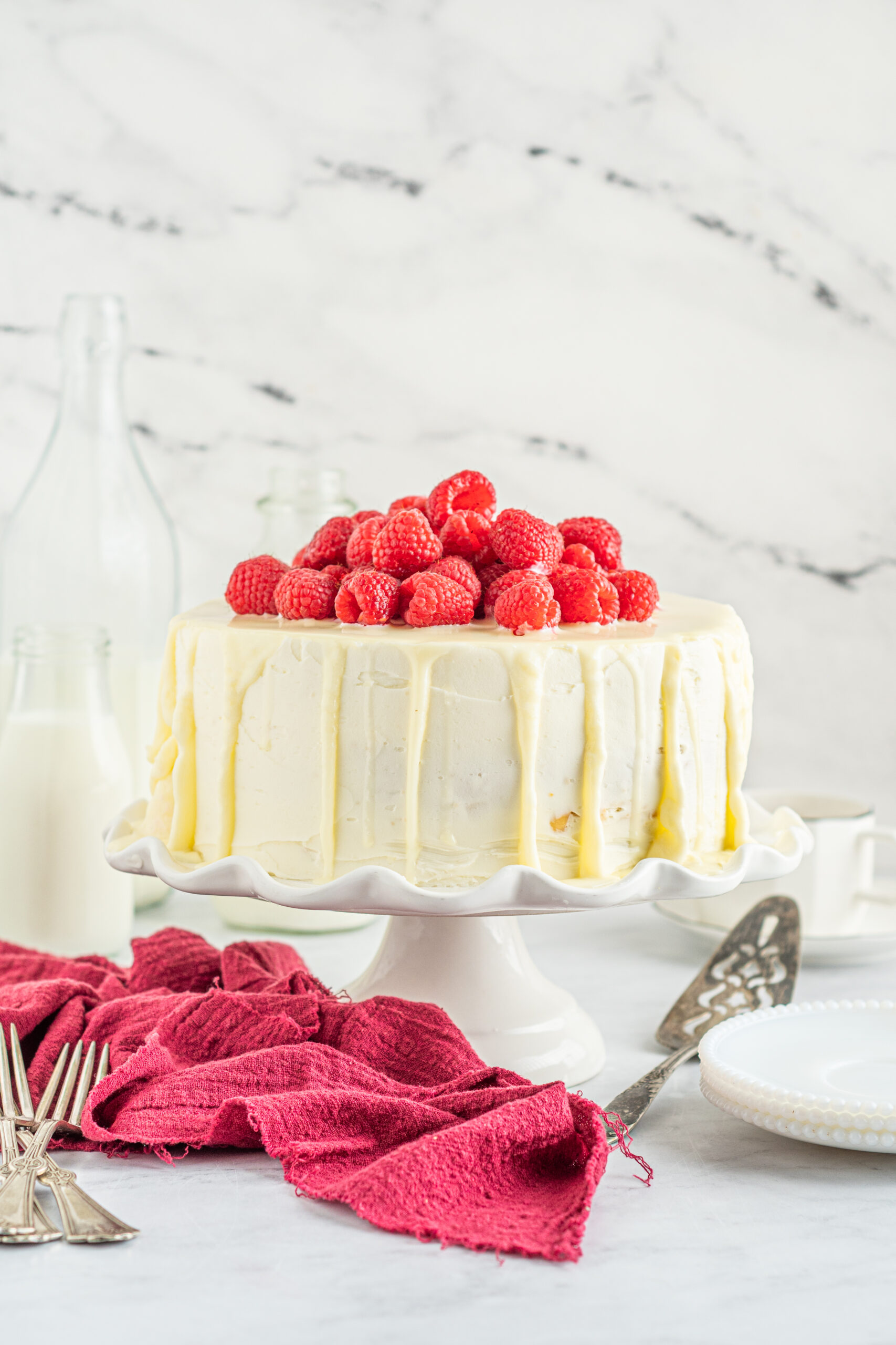 Front view of White Chocolate Cake with Raspberries on a white cake stand.