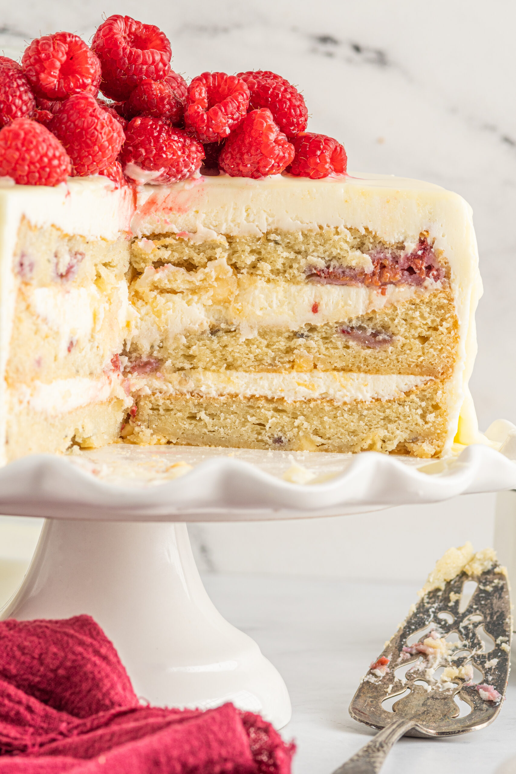 Front view of White Chocolate Cake with Raspberries on a white cake stand.