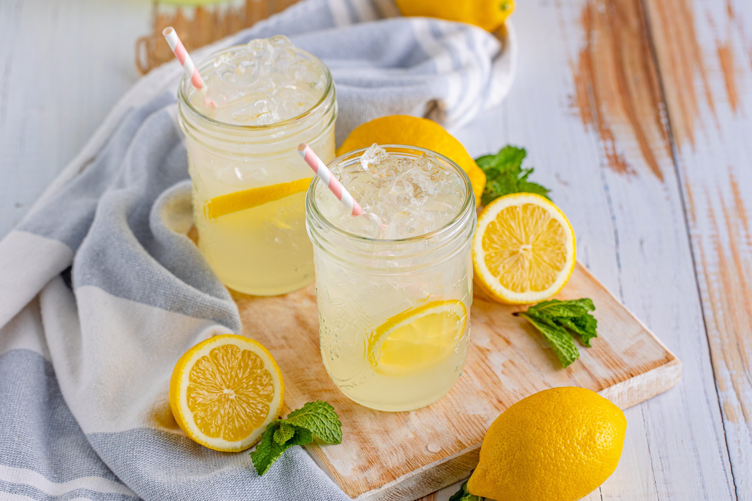Front view of Homemade Lemonade in two mason jars garnished with lemon slices.