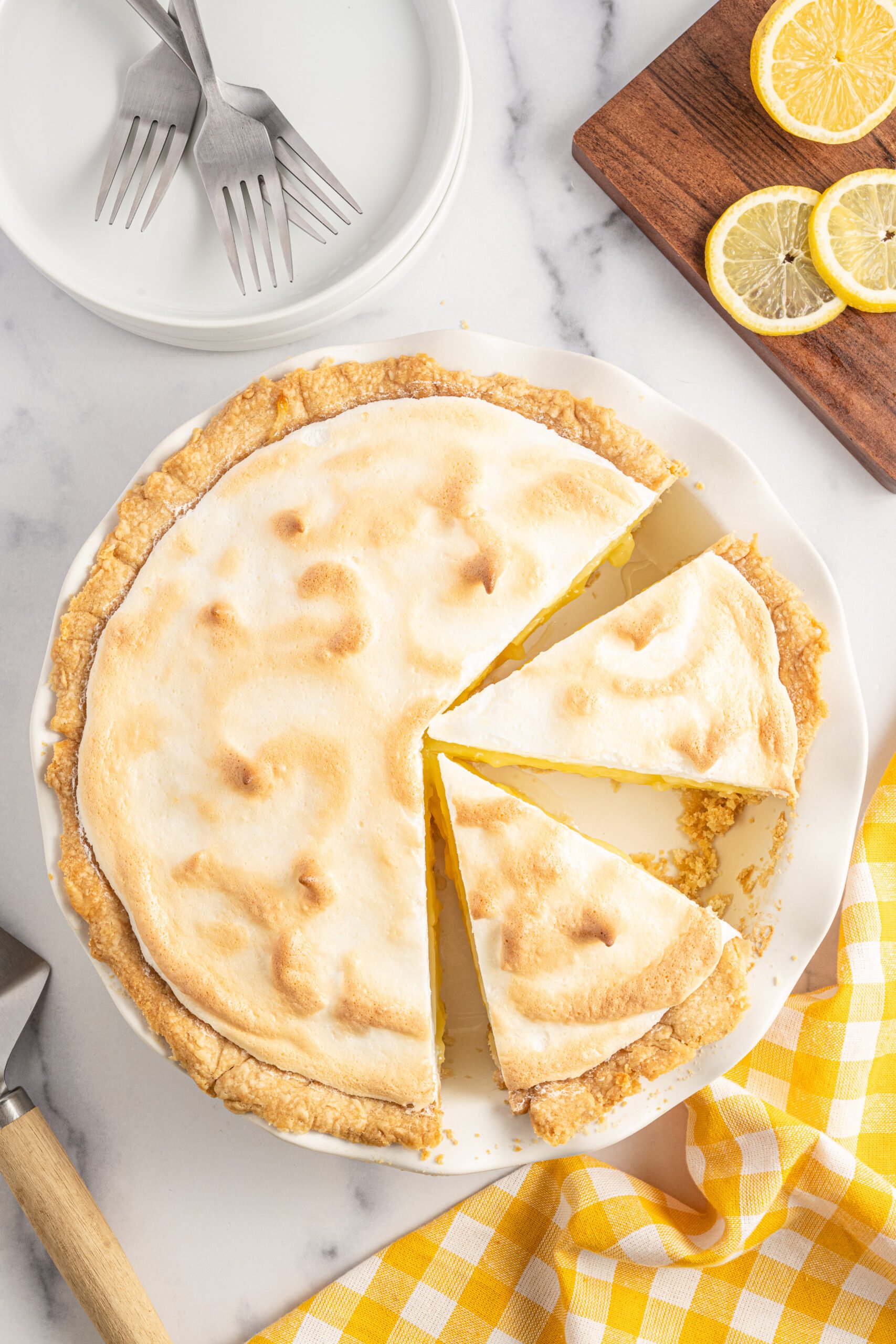 Overhead shot of two slices of lemon meringue pie in a white pie dish. 