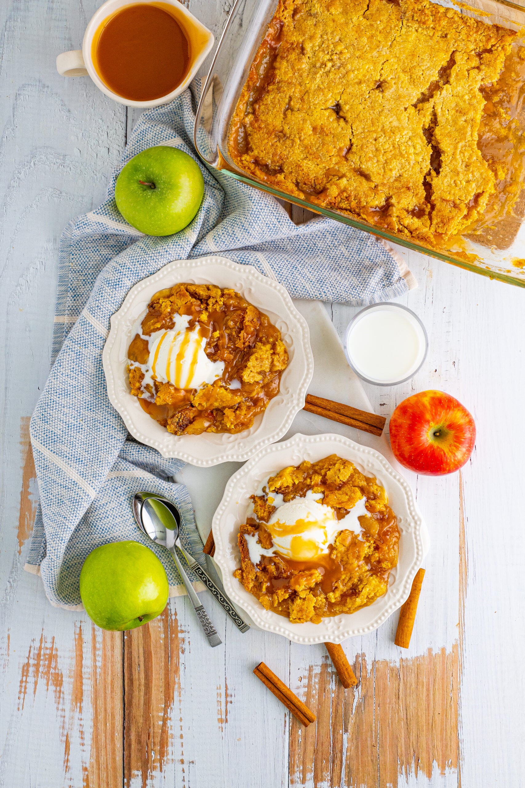 Overhead shot of Caramel Apple Dump Cake on two white plates with a blue and white linen.