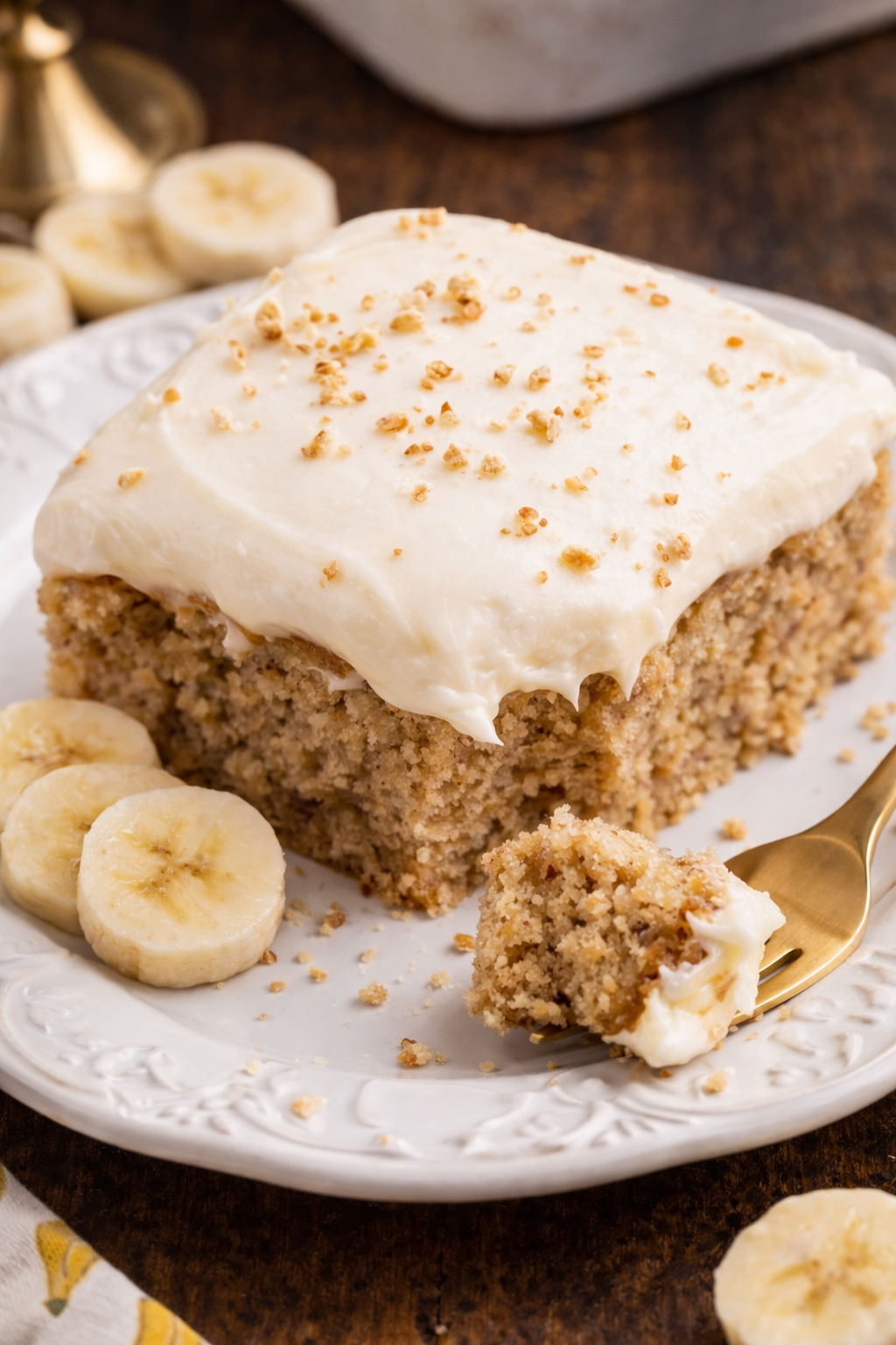 Banana Sheet Cake on a white plate with a bite missing 