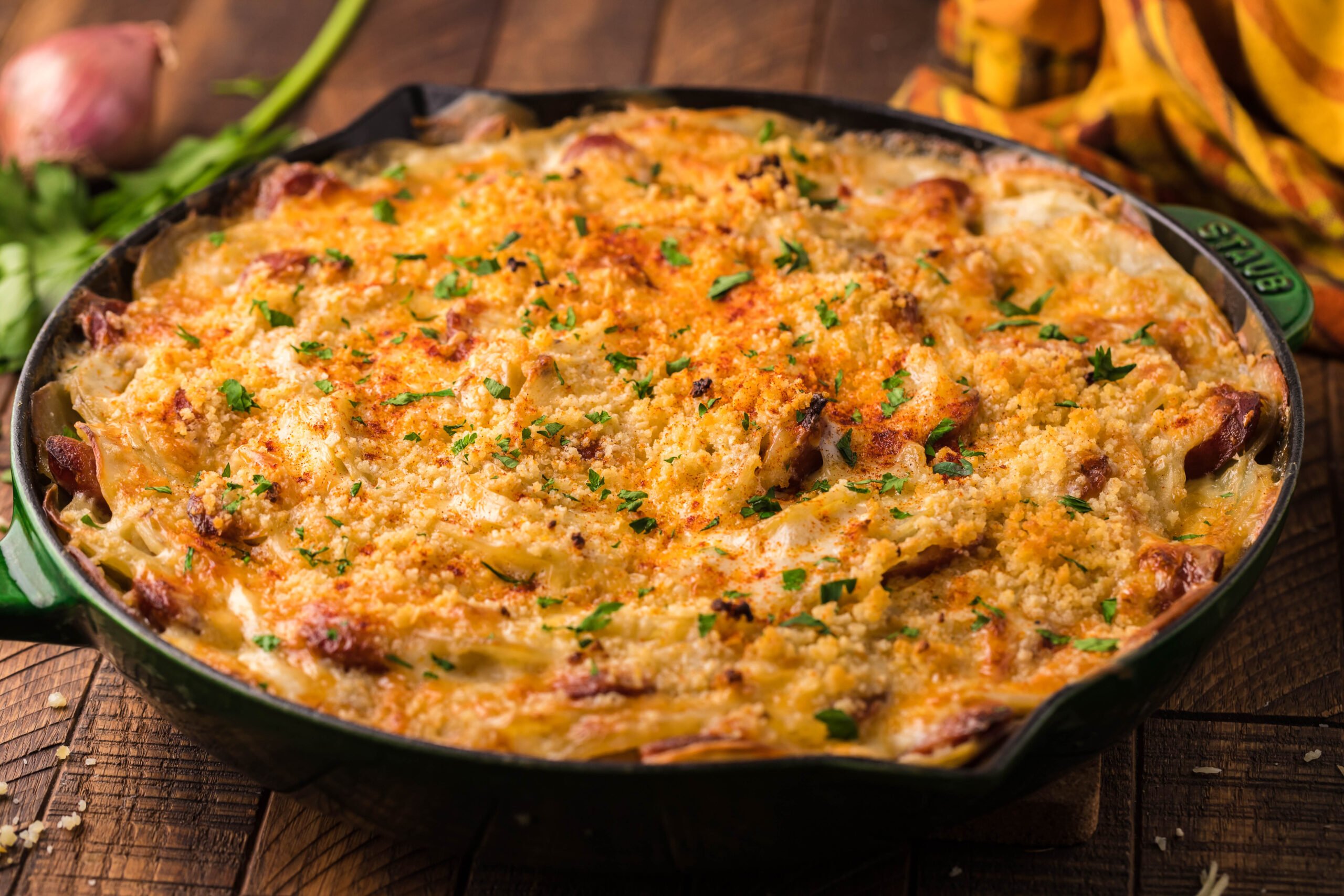 side view Au Gratin Potatoes & Sausage in a cast iron skillet on a wooden table
