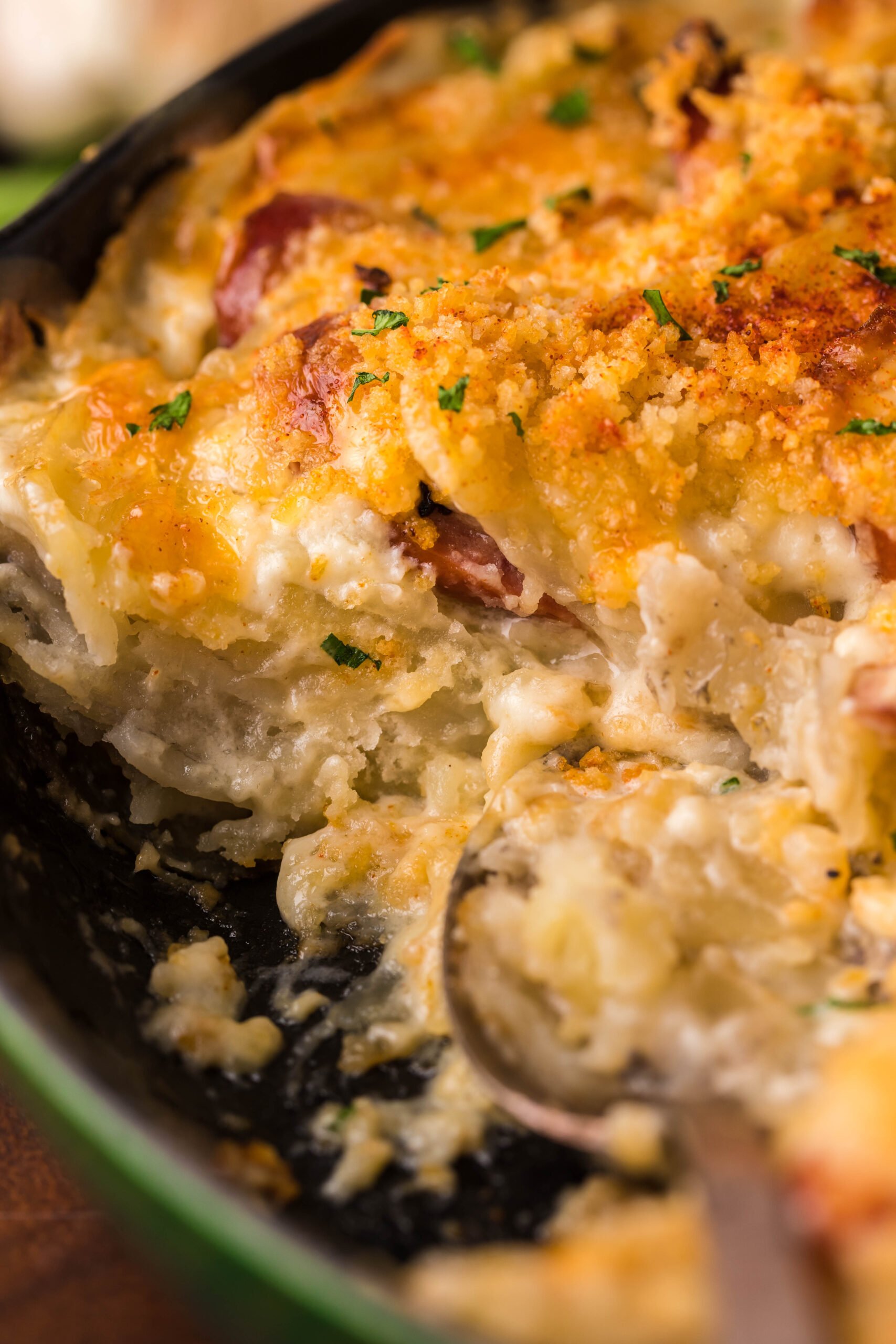 Close up view of Au Gratin Potatoes & Ham in a cast iron skillet with a serving removed.